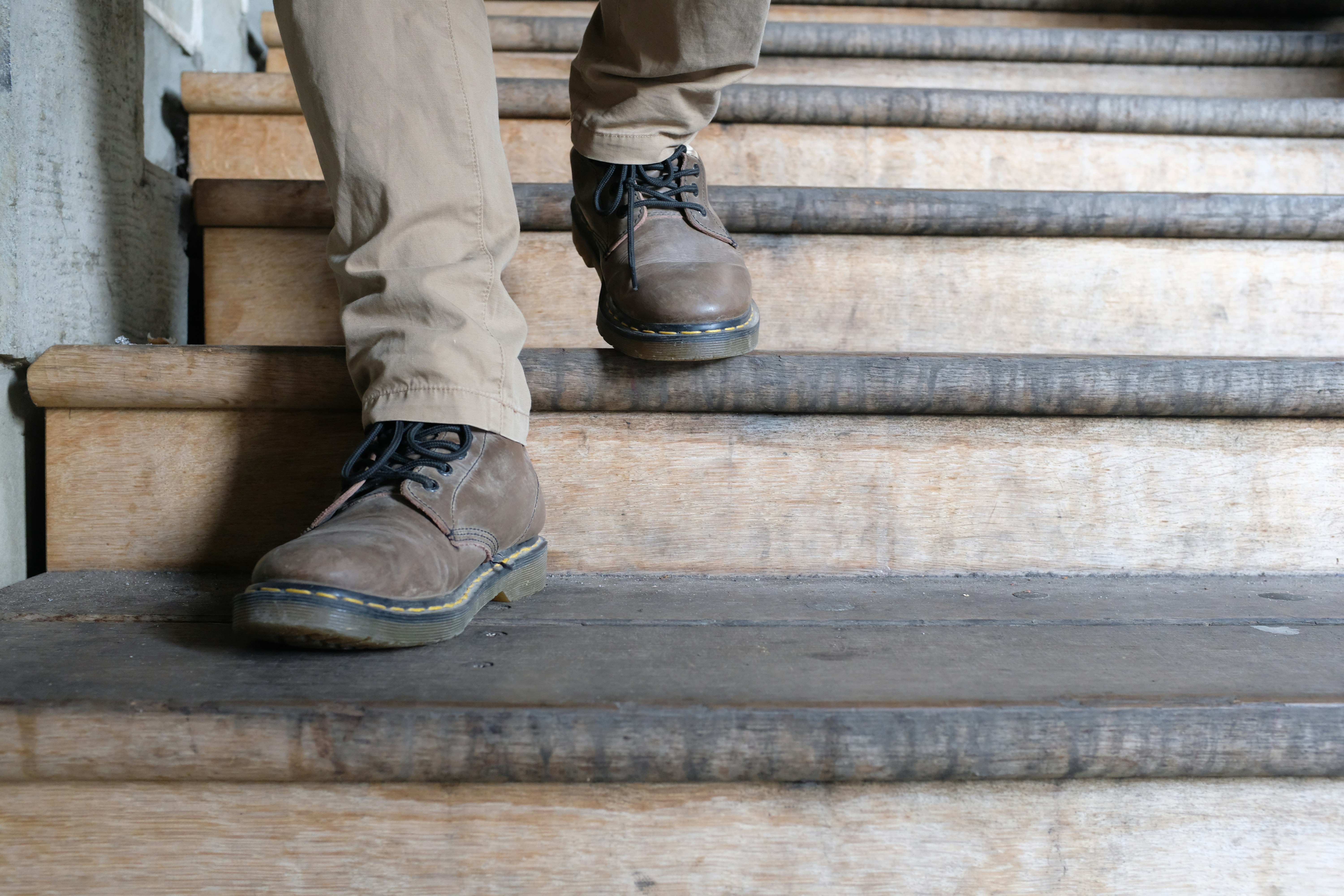 Person descends wooden stairs, shoes in focus.