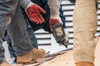 Workers are using a drill on a roof.