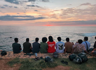 Friends watch the sunset over the ocean.
