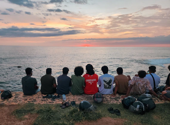 Friends watch the sunset over the ocean.