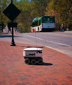 A delivery robot rolls on a sidewalk.