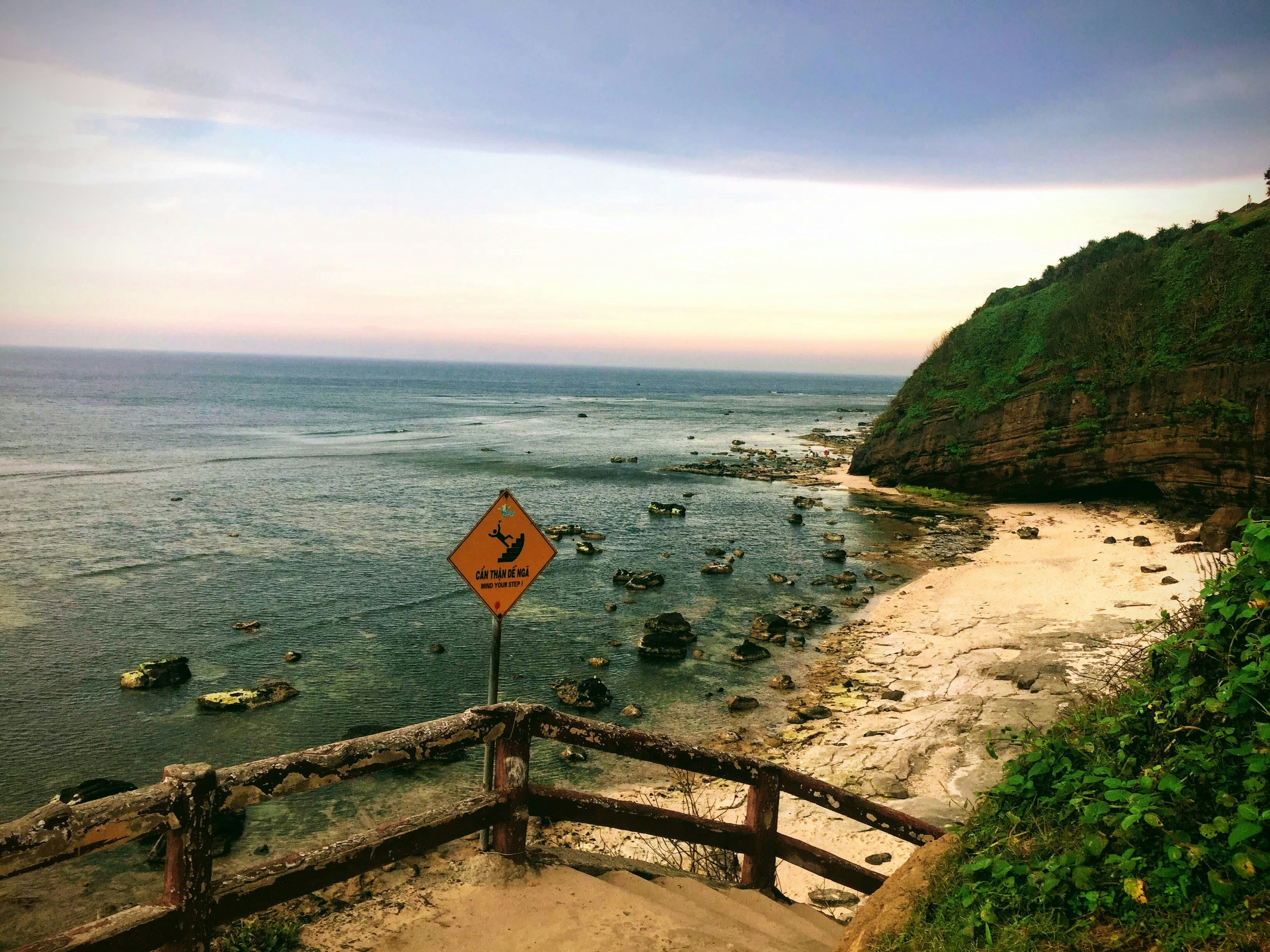 Coastal view with a sign warning about rocks.