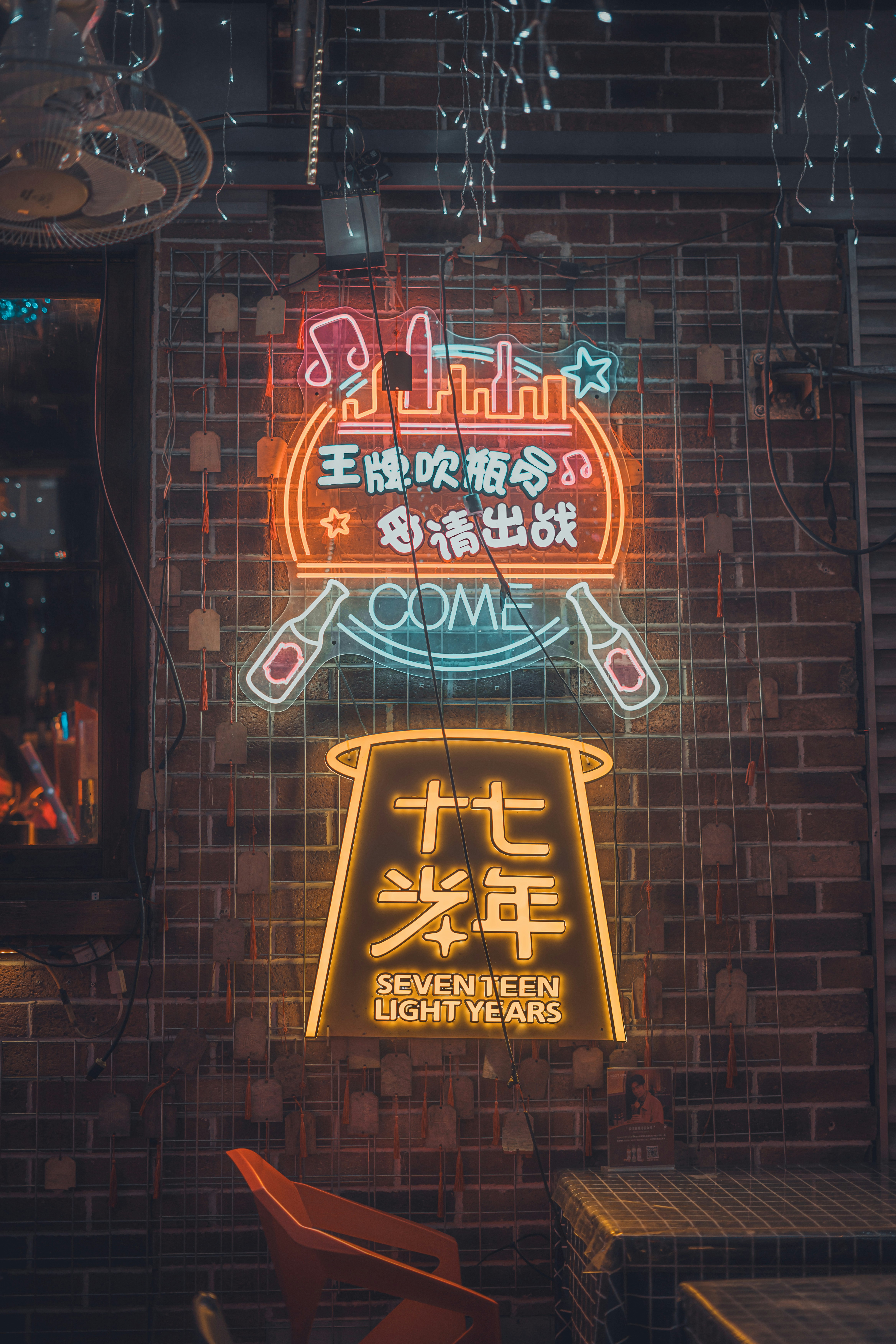 Neon signs illuminate a bar's brick wall.