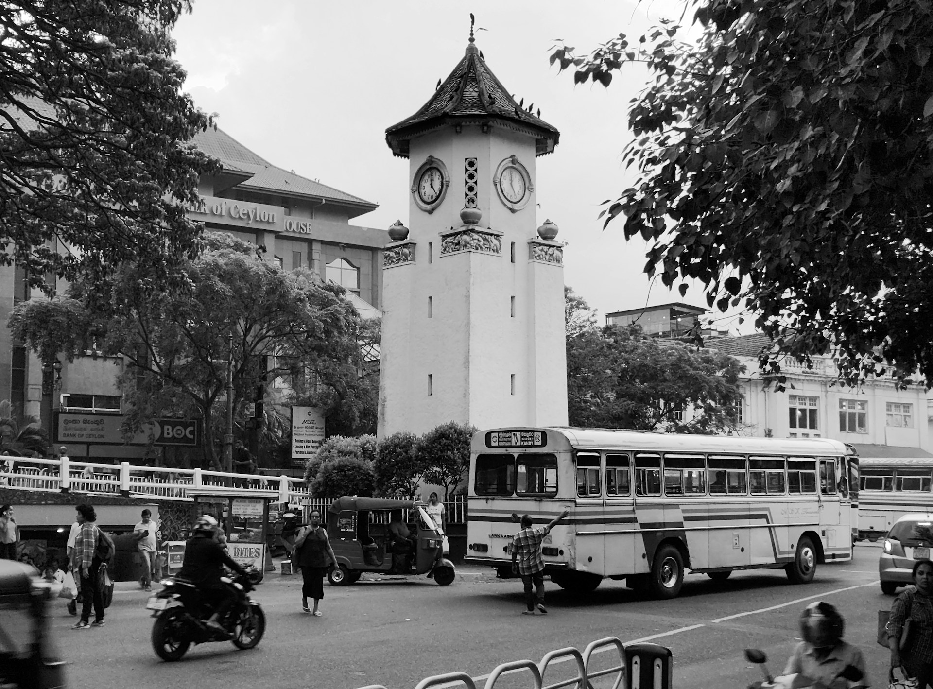 A clock tower stands tall in a busy street.