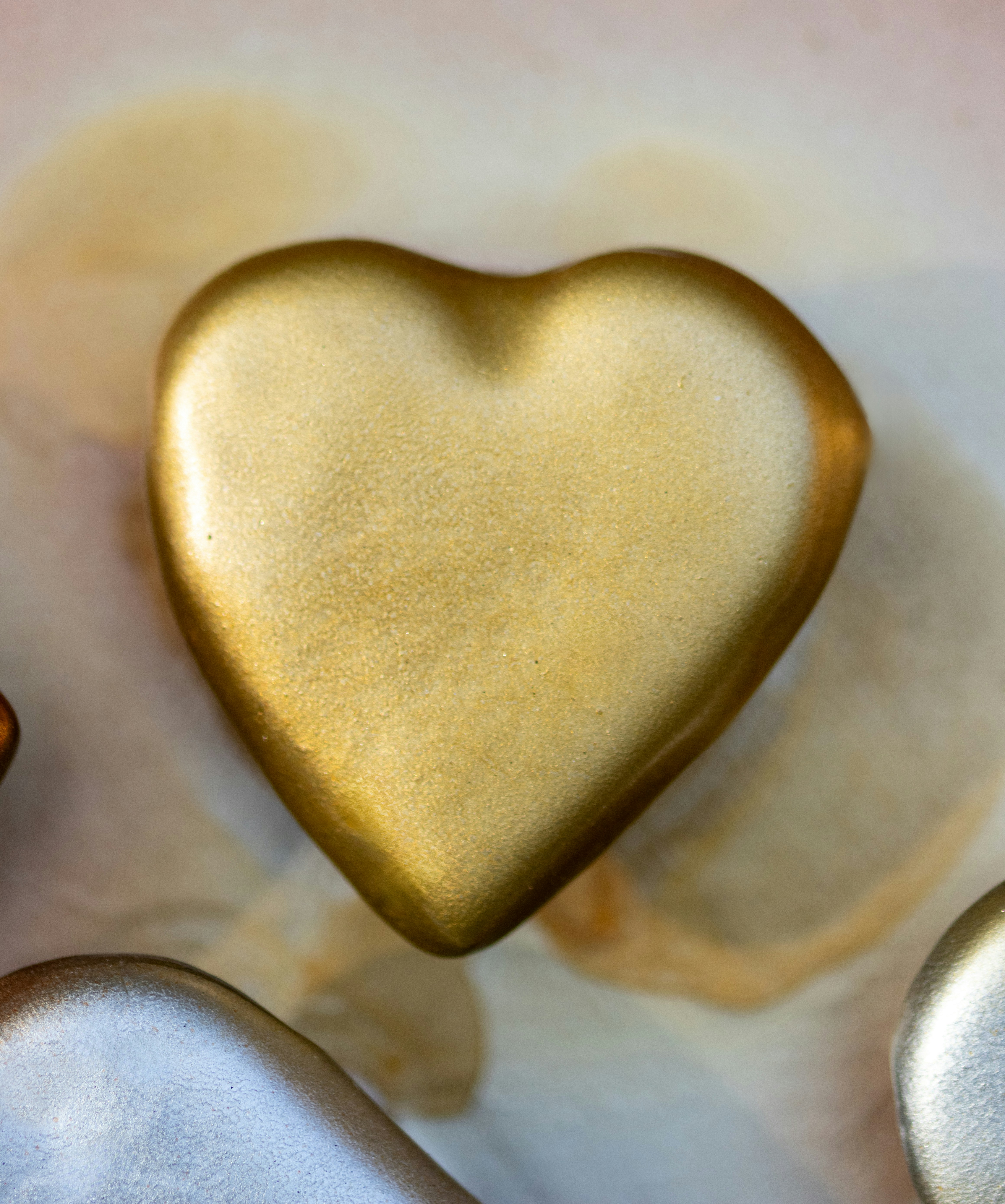 A golden heart sits on a soft, neutral surface.