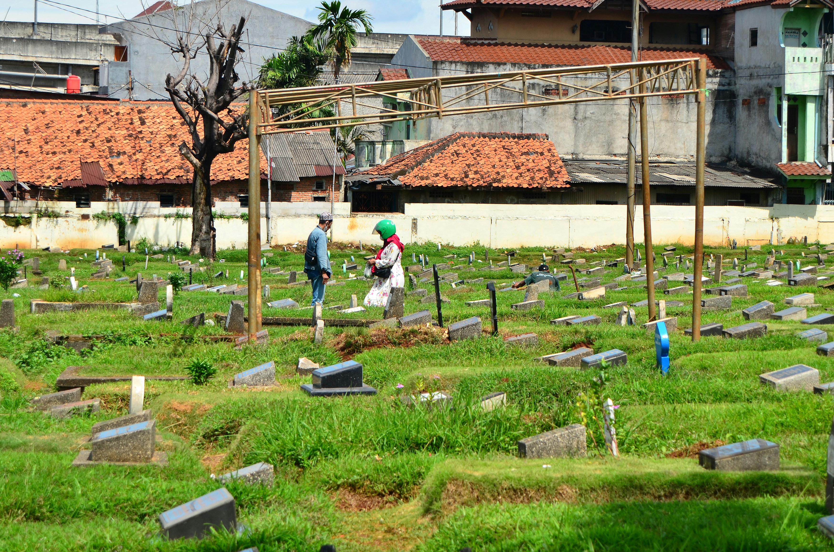People stand near graves in a cemetery.