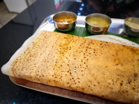 A delicious dosa is served with sides.