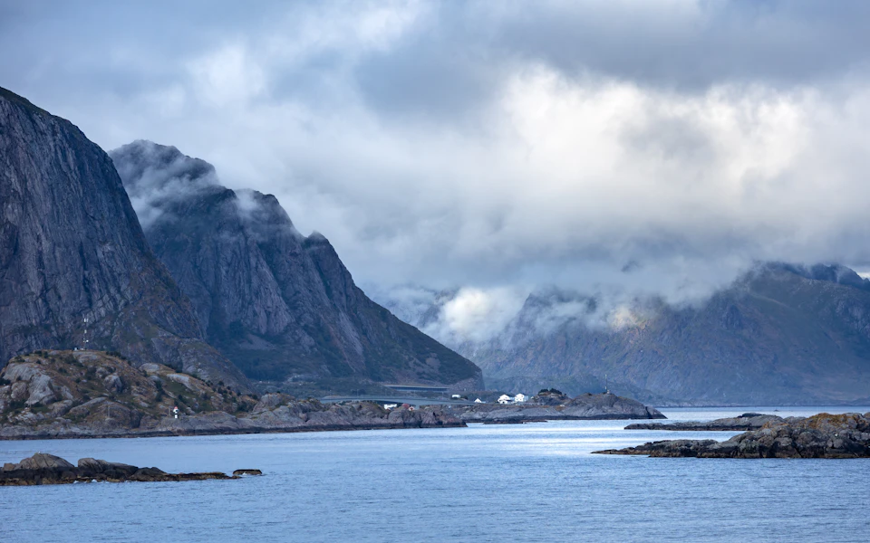 Serene mountainous landscape with water nestled between two towering mountains under soft cloudy sky