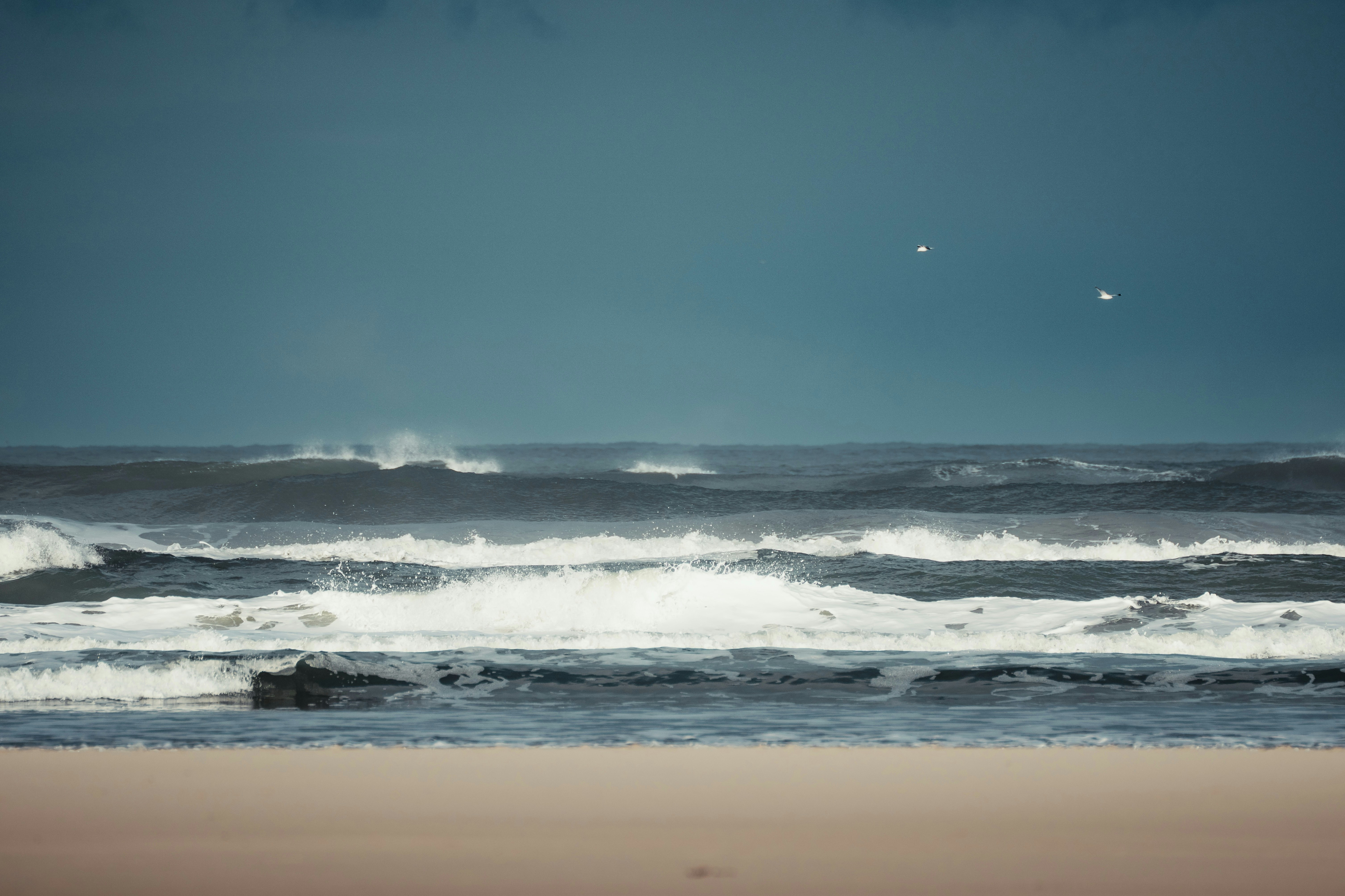 Rough waves crash on the shore under a cloudy sky.