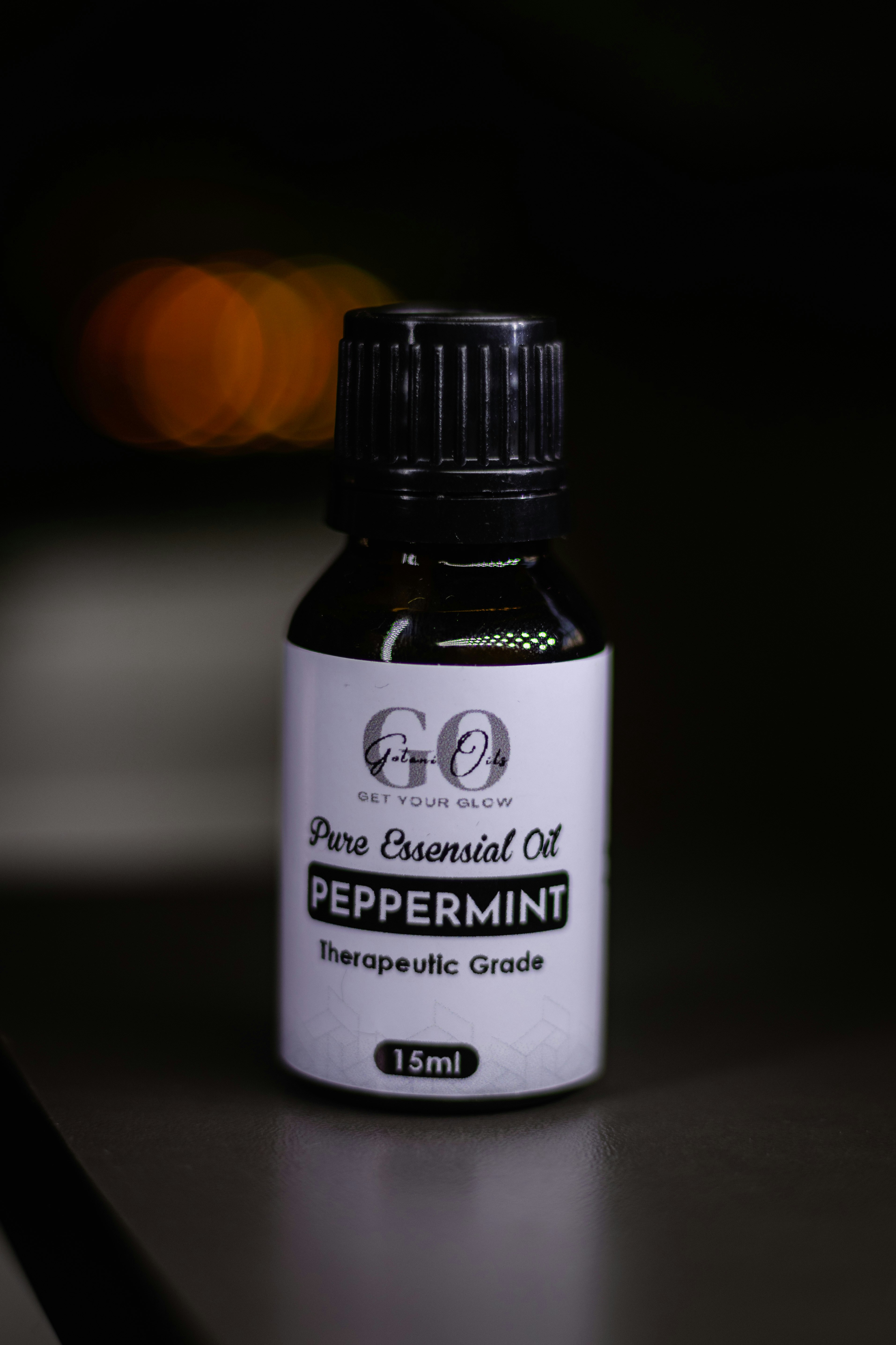 Peppermint essential oil bottle stands alone in dark.