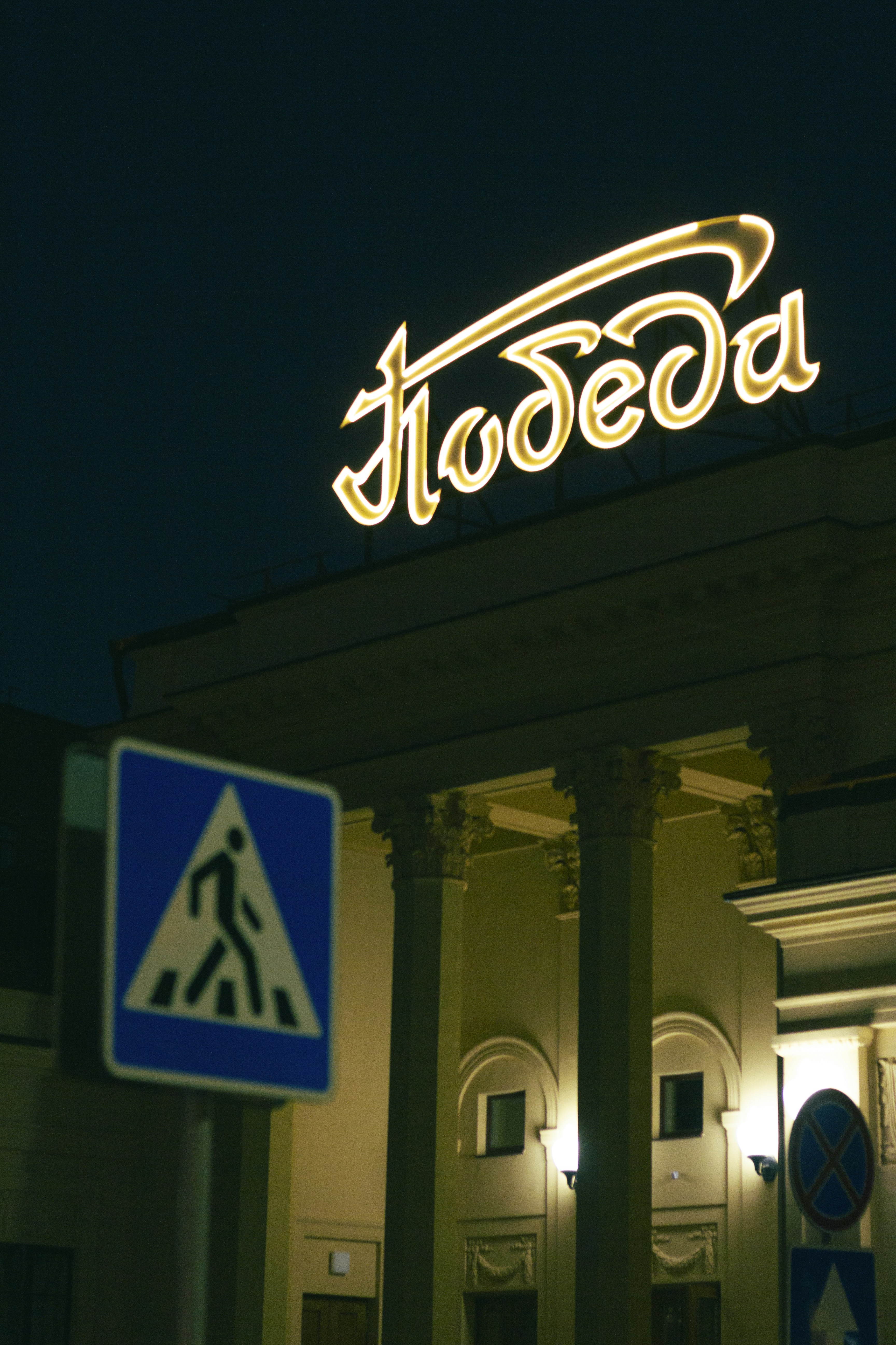 A lit sign over an ornate building at night.