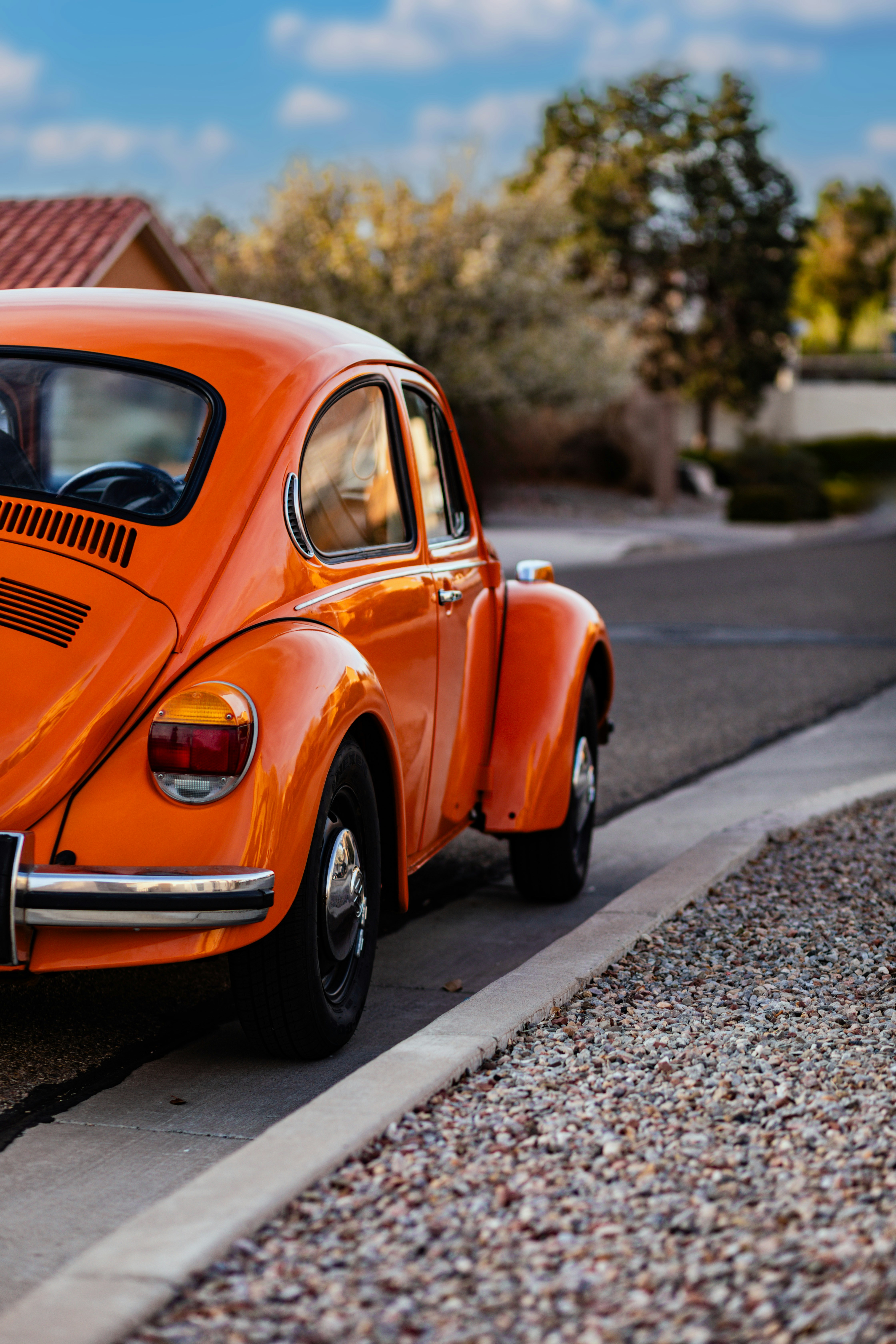 Orange volkswagen beetle parked by the roadside.