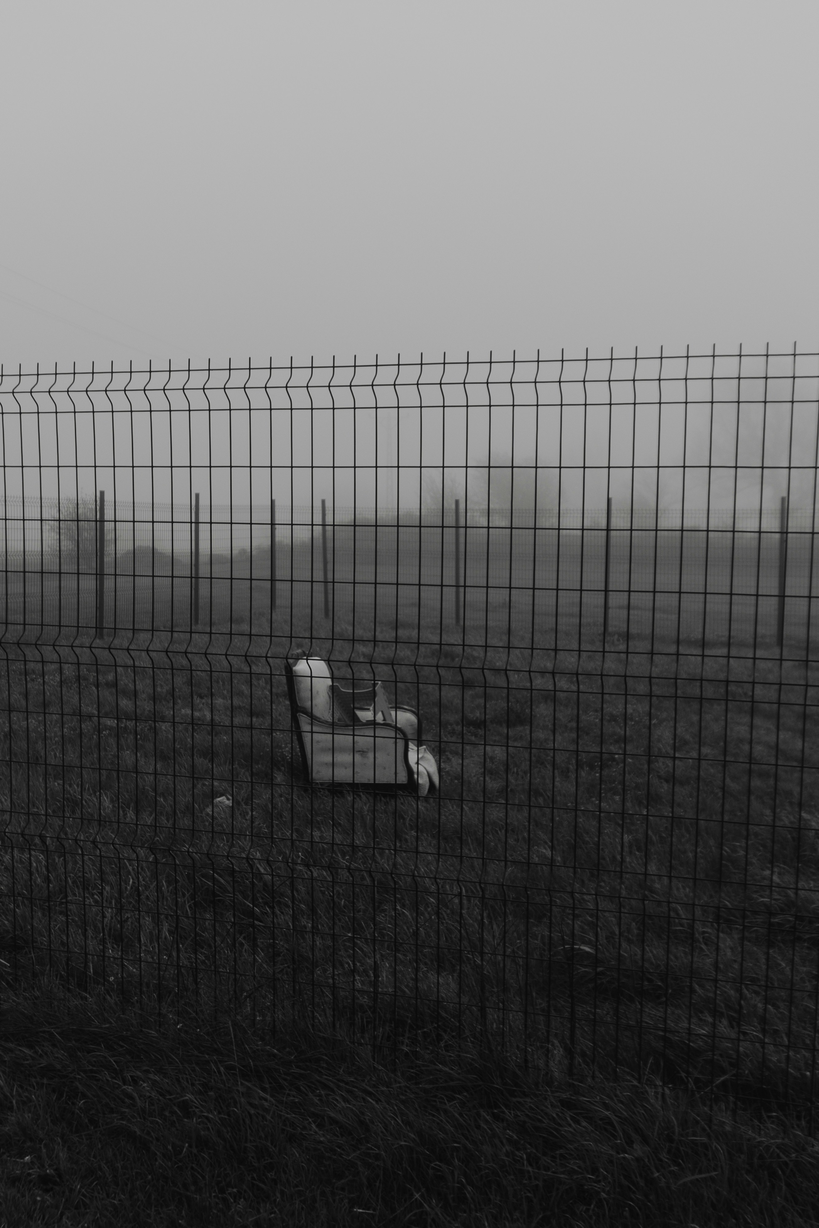 Abandoned chair behind a fence in fog.