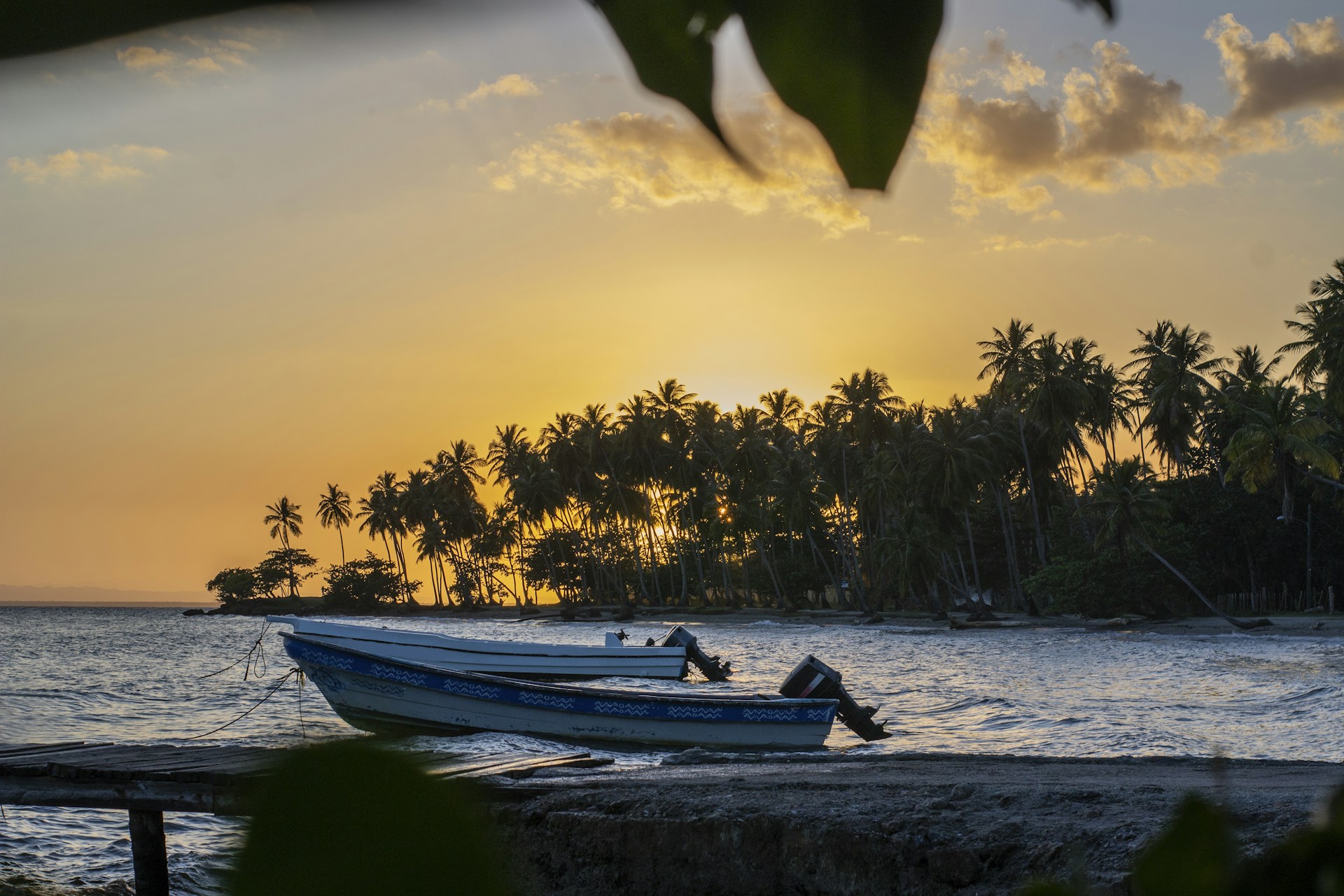 Boats sit on the shore at sunset.