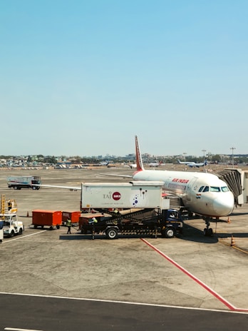 An airplane sits at the airport with ground crew.