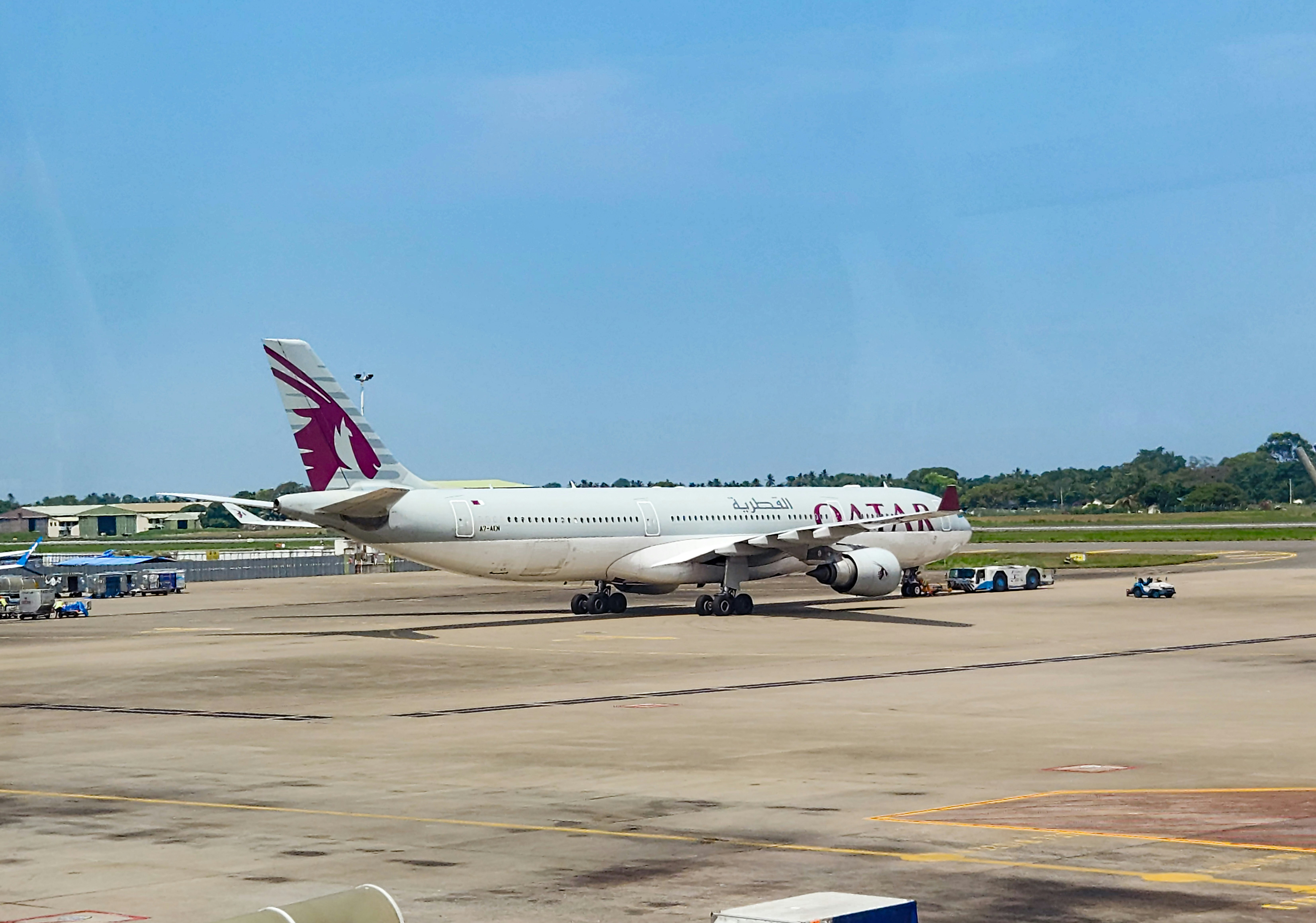A qatar airways plane sits on the tarmac., A Qatar Airways wide-body aircraft, an Airbus A330, stationary on the airport tarmac.