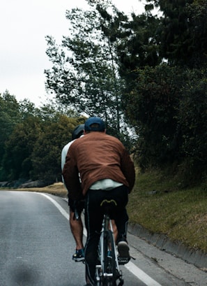 Two cyclists ride along a road.