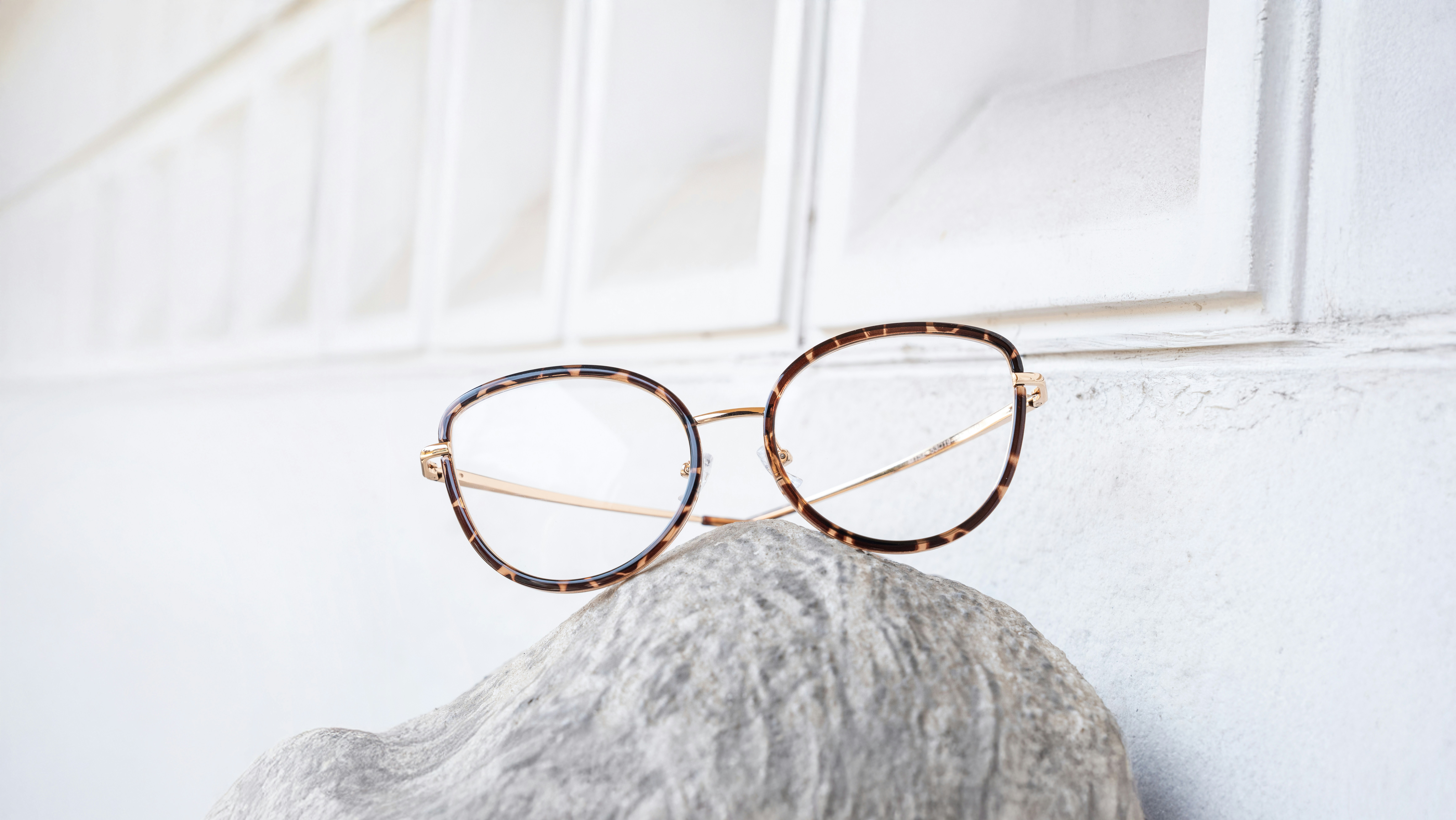 Die Brille ruht auf einem strukturierten, hellen Objekt.