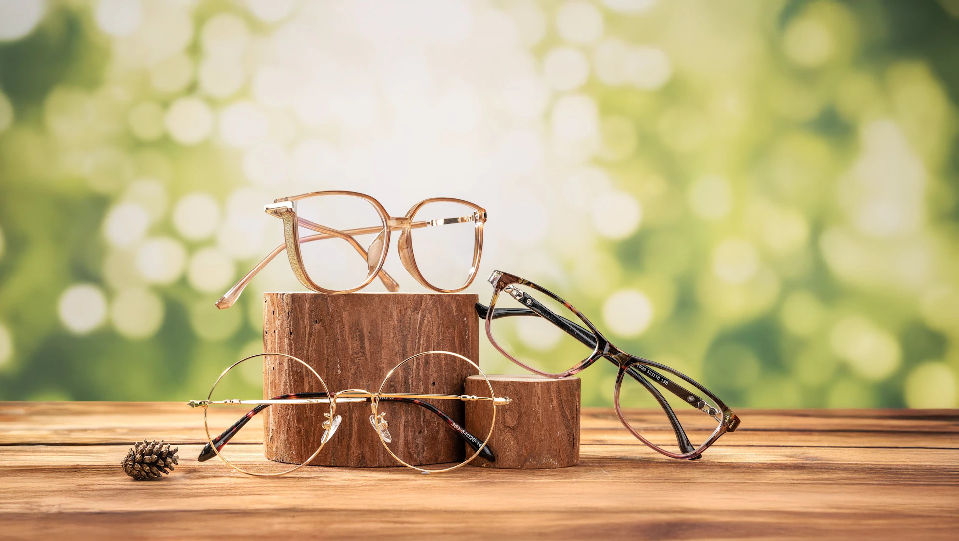 Eyeglasses displayed on wooden blocks against greenery.