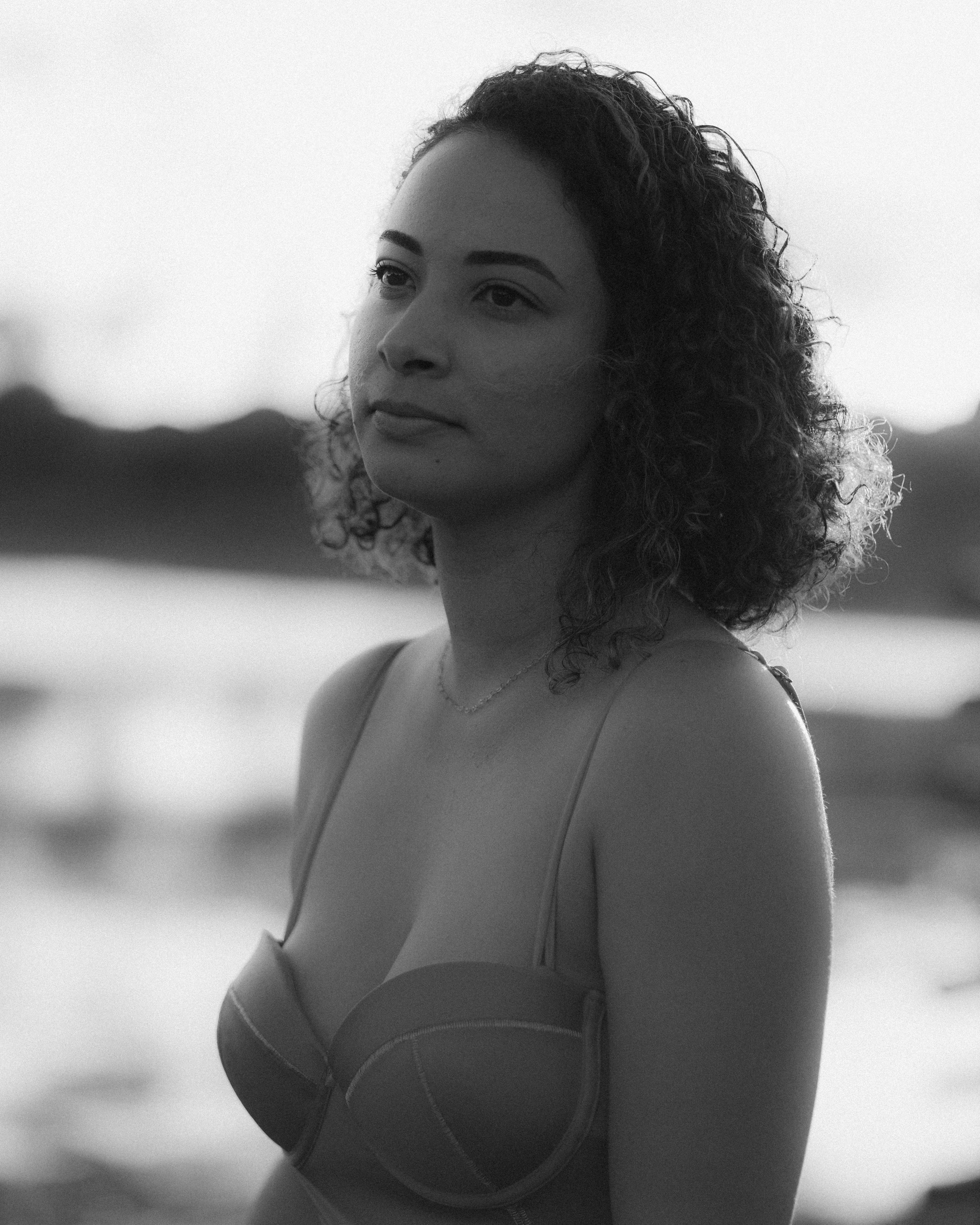 Woman with curly hair gazes thoughtfully into the distance.