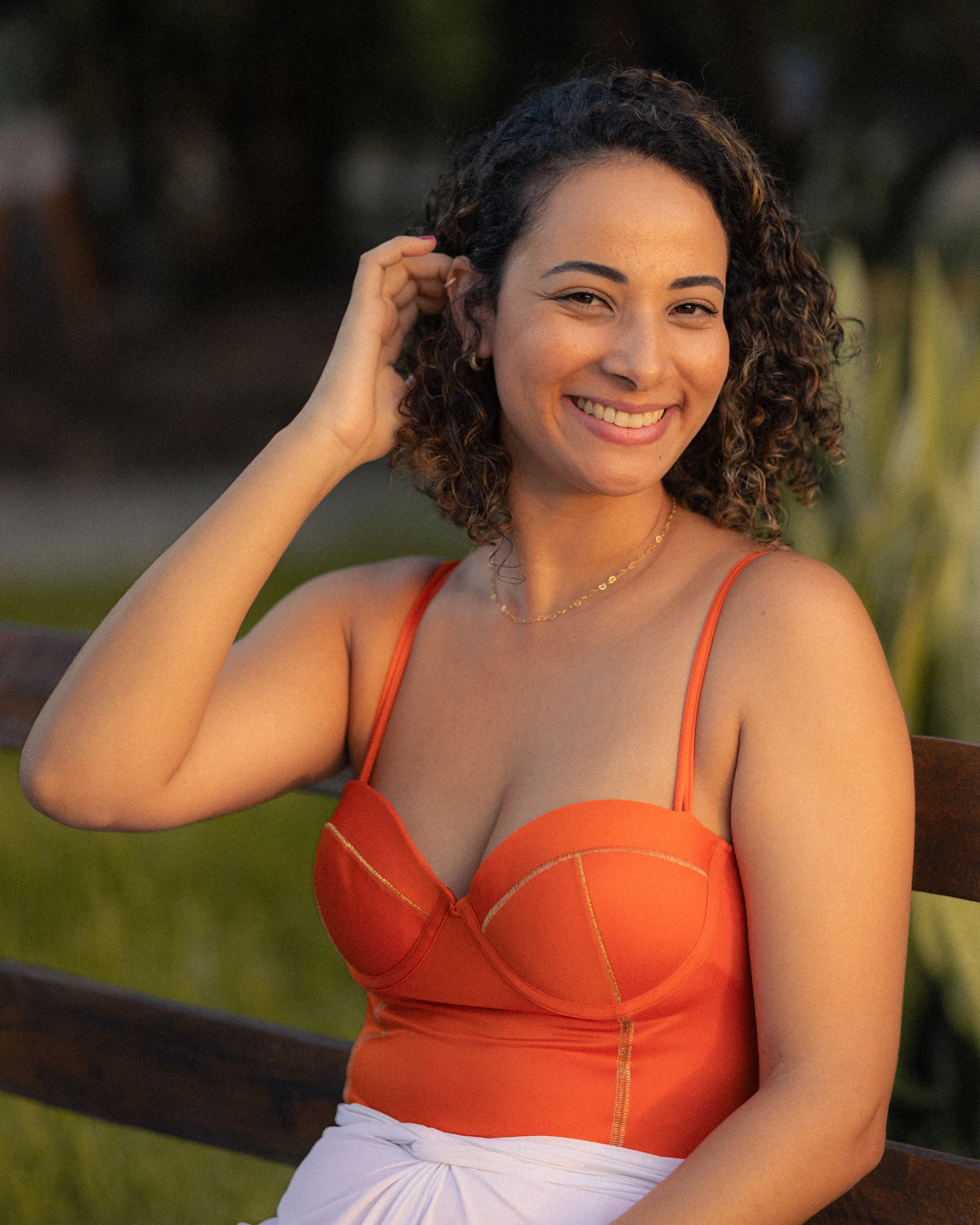 Adult woman with curly hair smiling warmly in golden-hour light