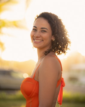 A woman smiles at the camera in bright sunlight.