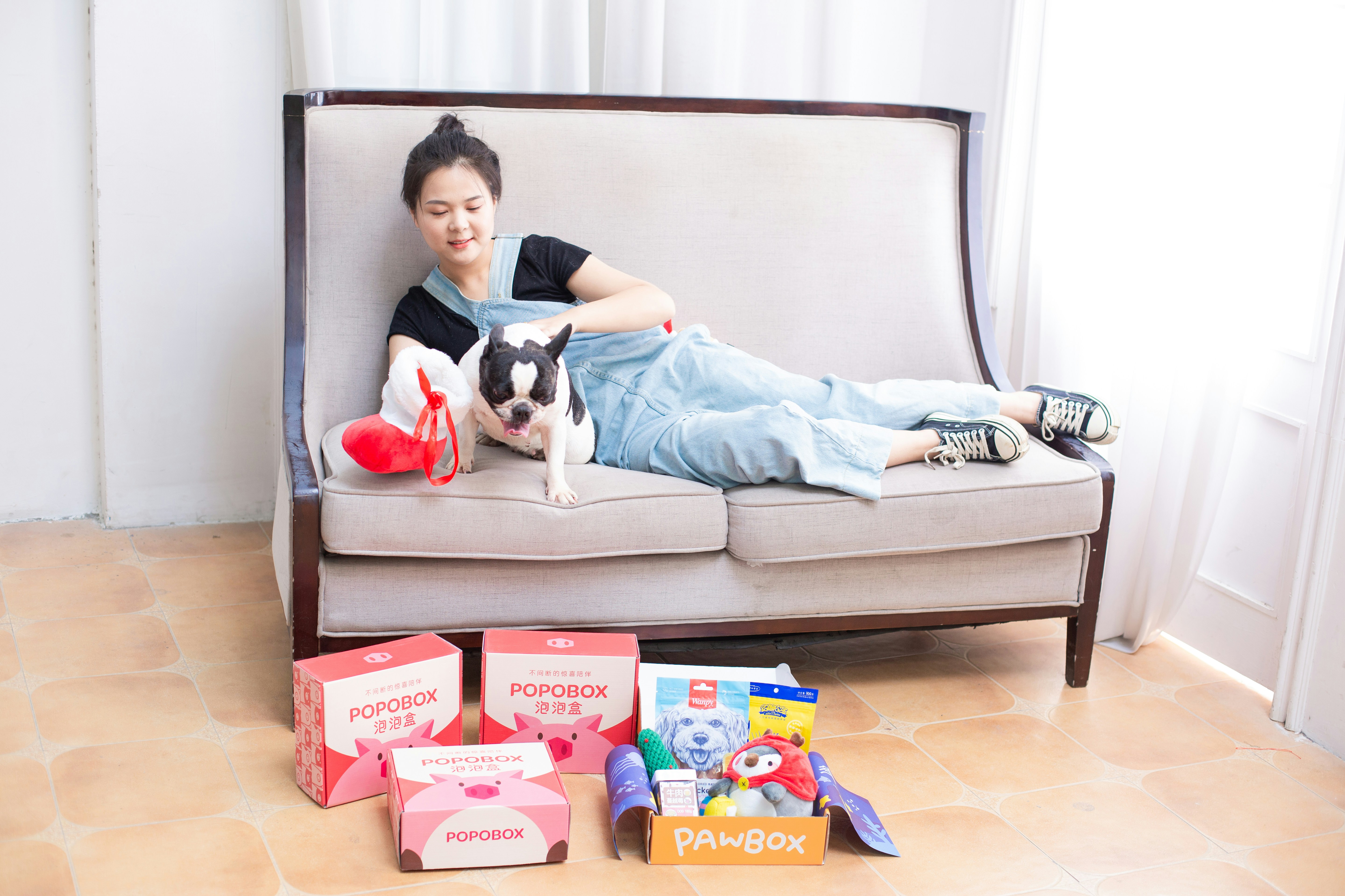 Une femme et un chien se détendent sur un canapé avec une boîte cadeau.