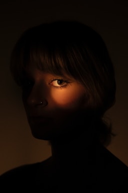 A woman's eye is lit by a warm glow.