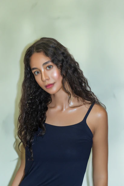 A beautiful woman poses with dark curly hair.