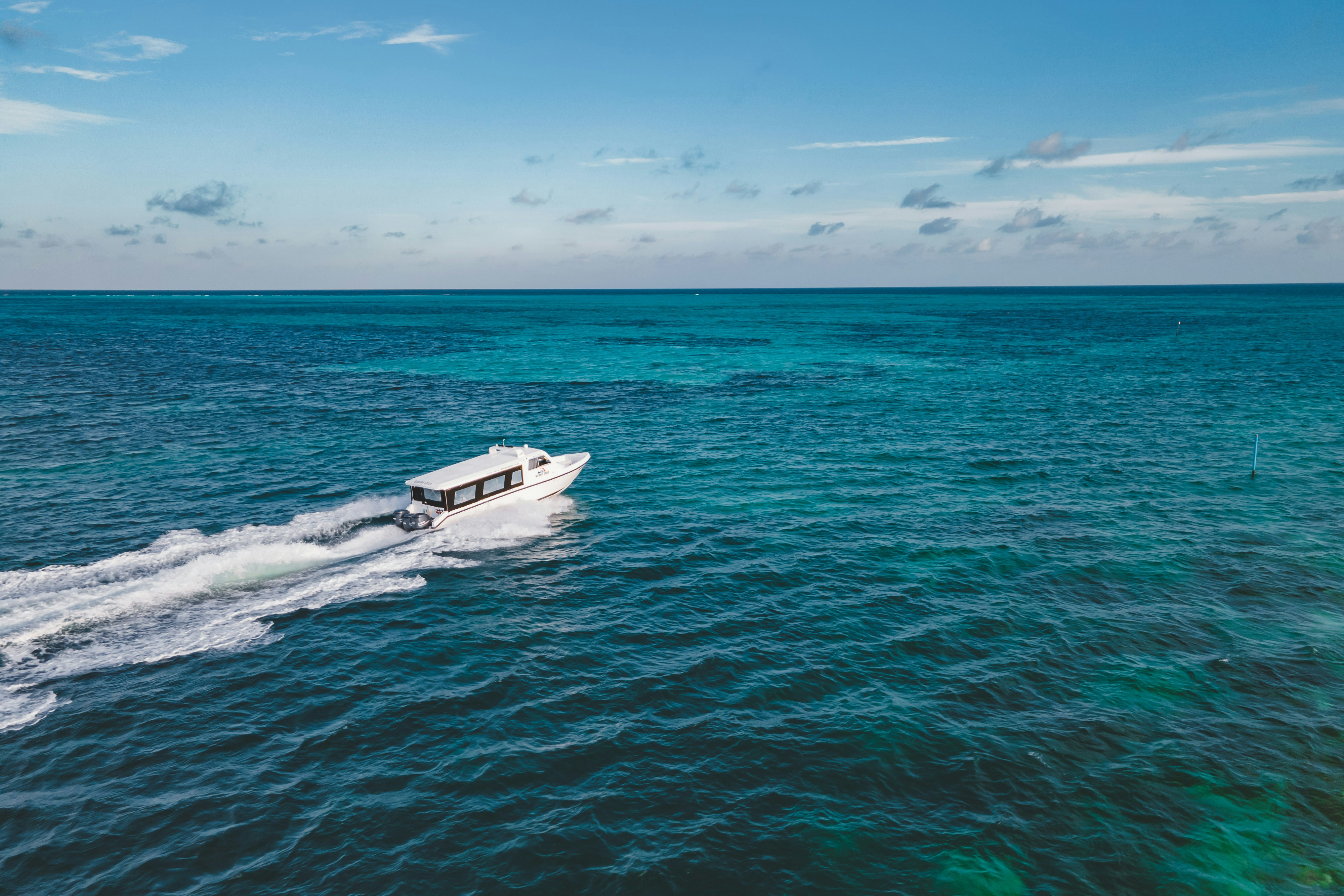 A boat speeds across a vast, blue ocean.