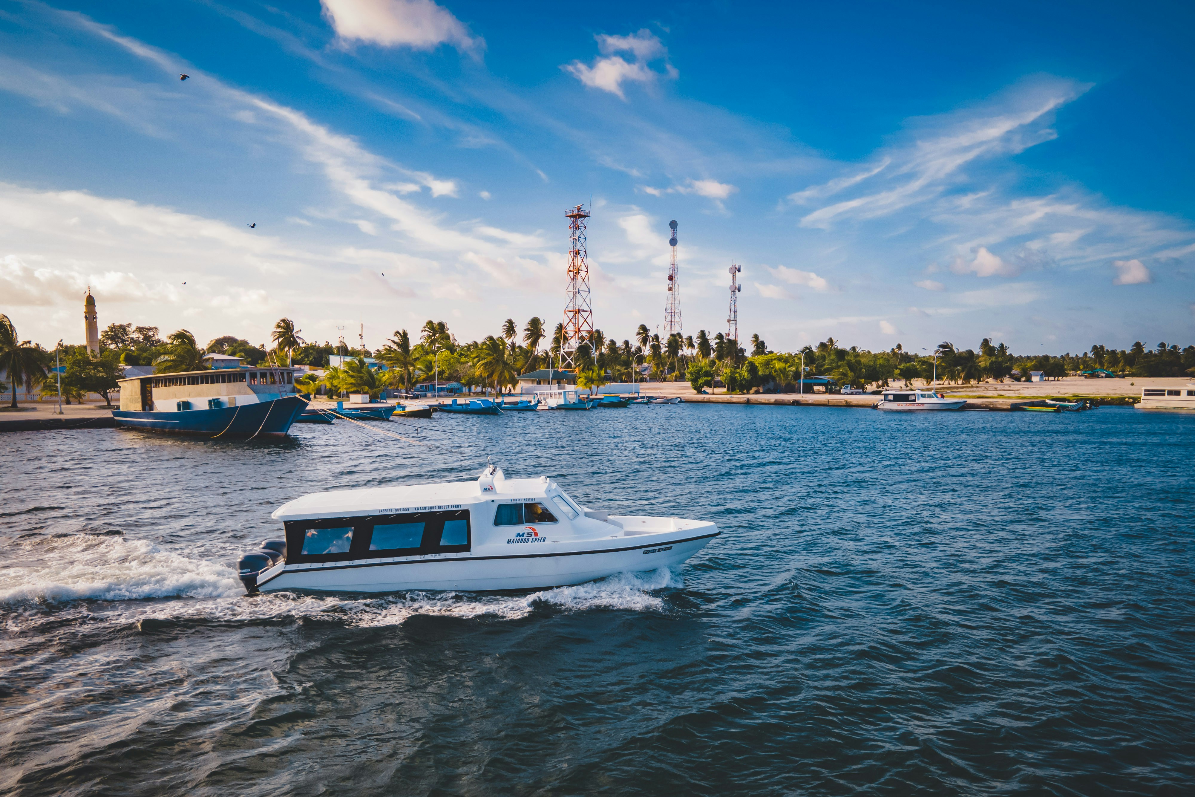 A boat sails across the sparkling ocean water.