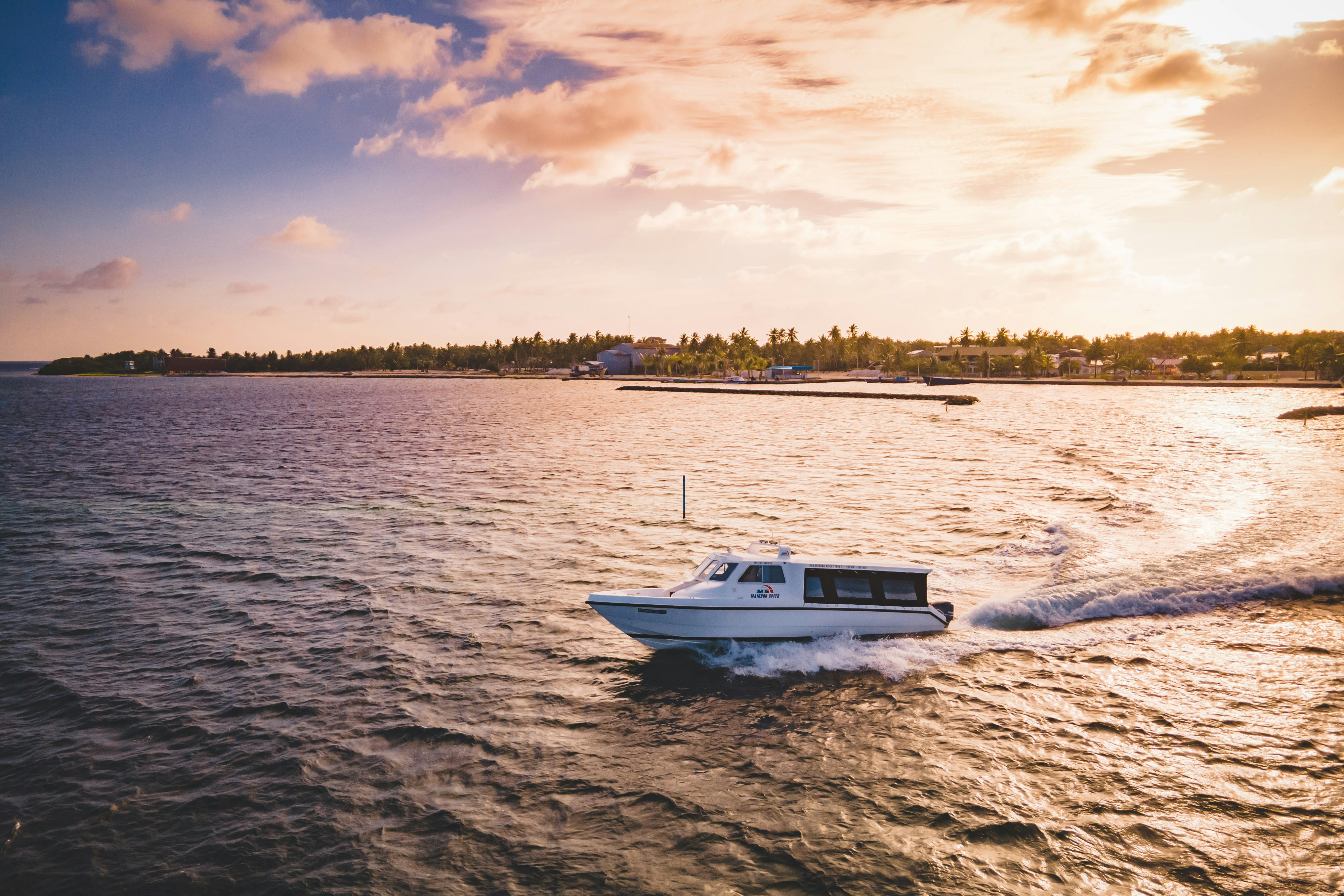 A boat glides on water near the coast.