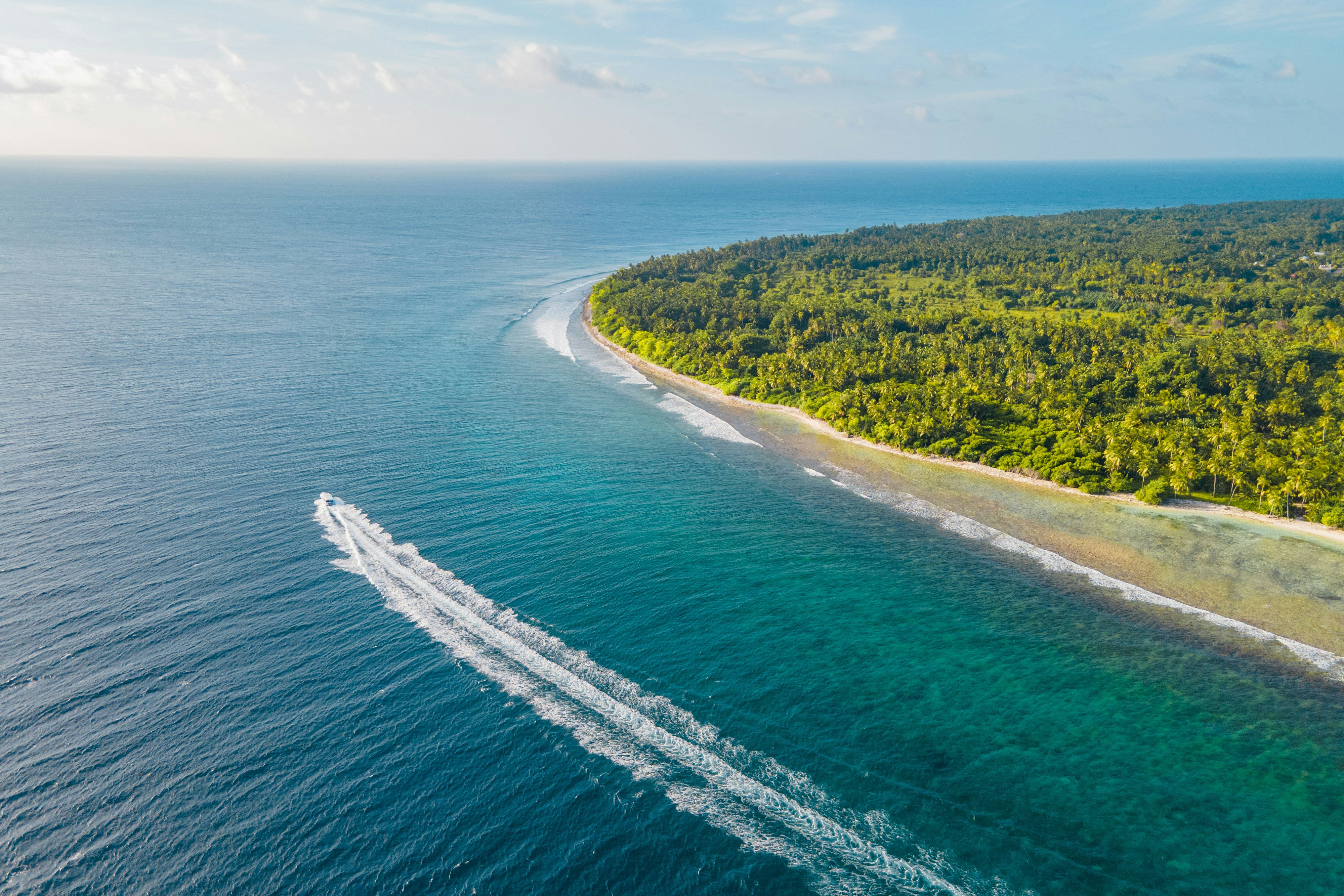 A boat speeds through crystal clear waters.