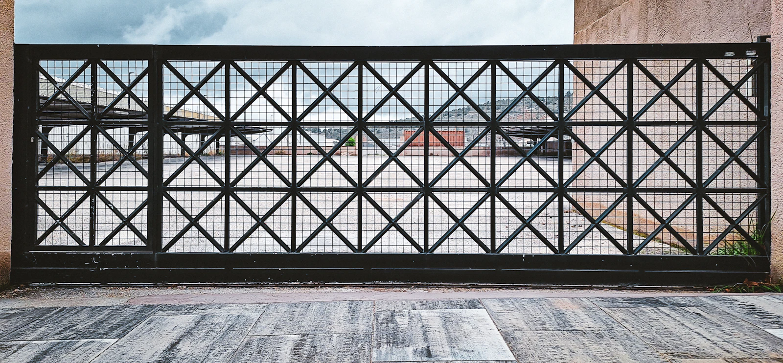 Referencia visual: portón metálico negro con patrón geométrico
