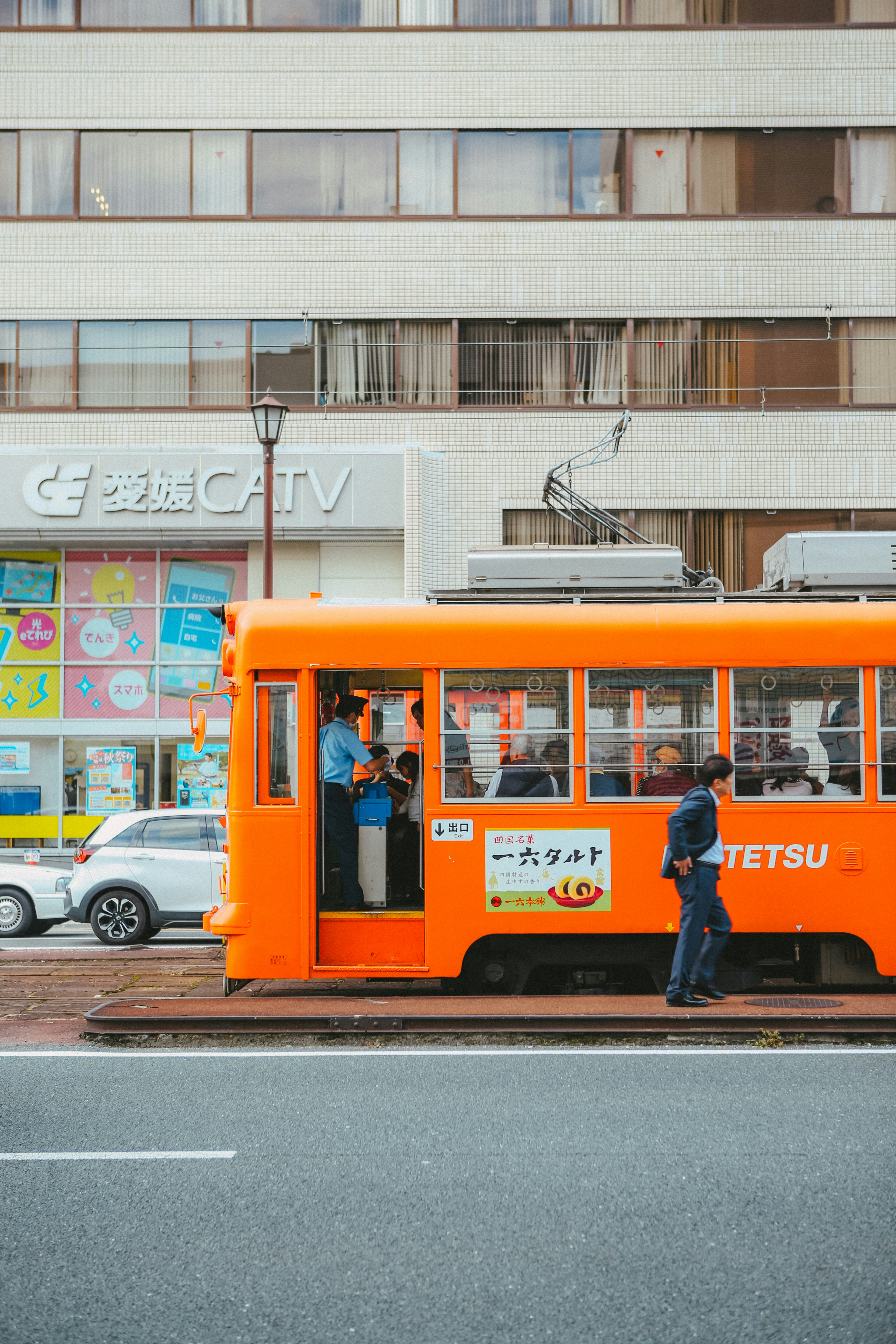 A bright orange tram is parked on the street.