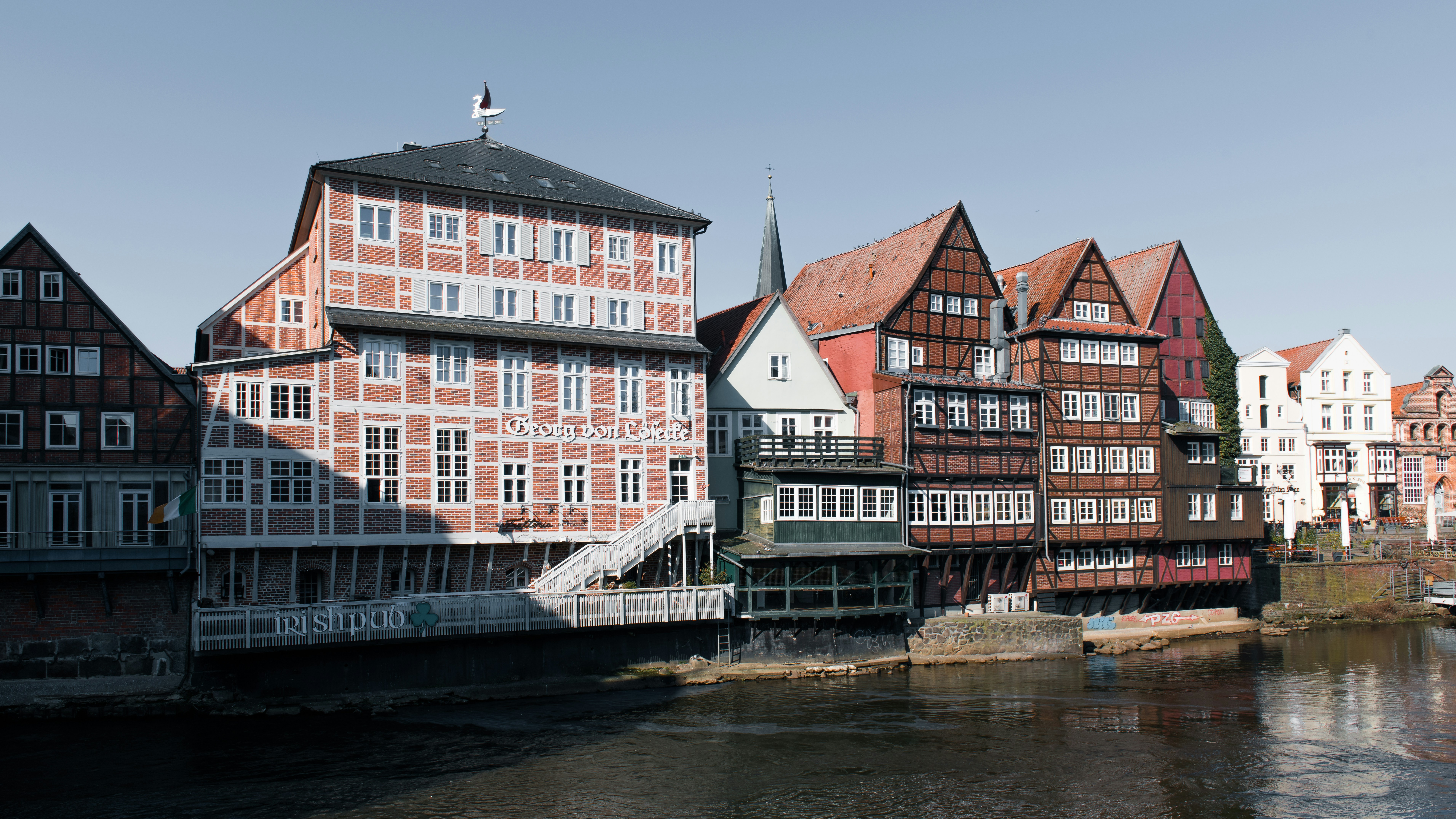 Historic buildings line a river in this scenic view.