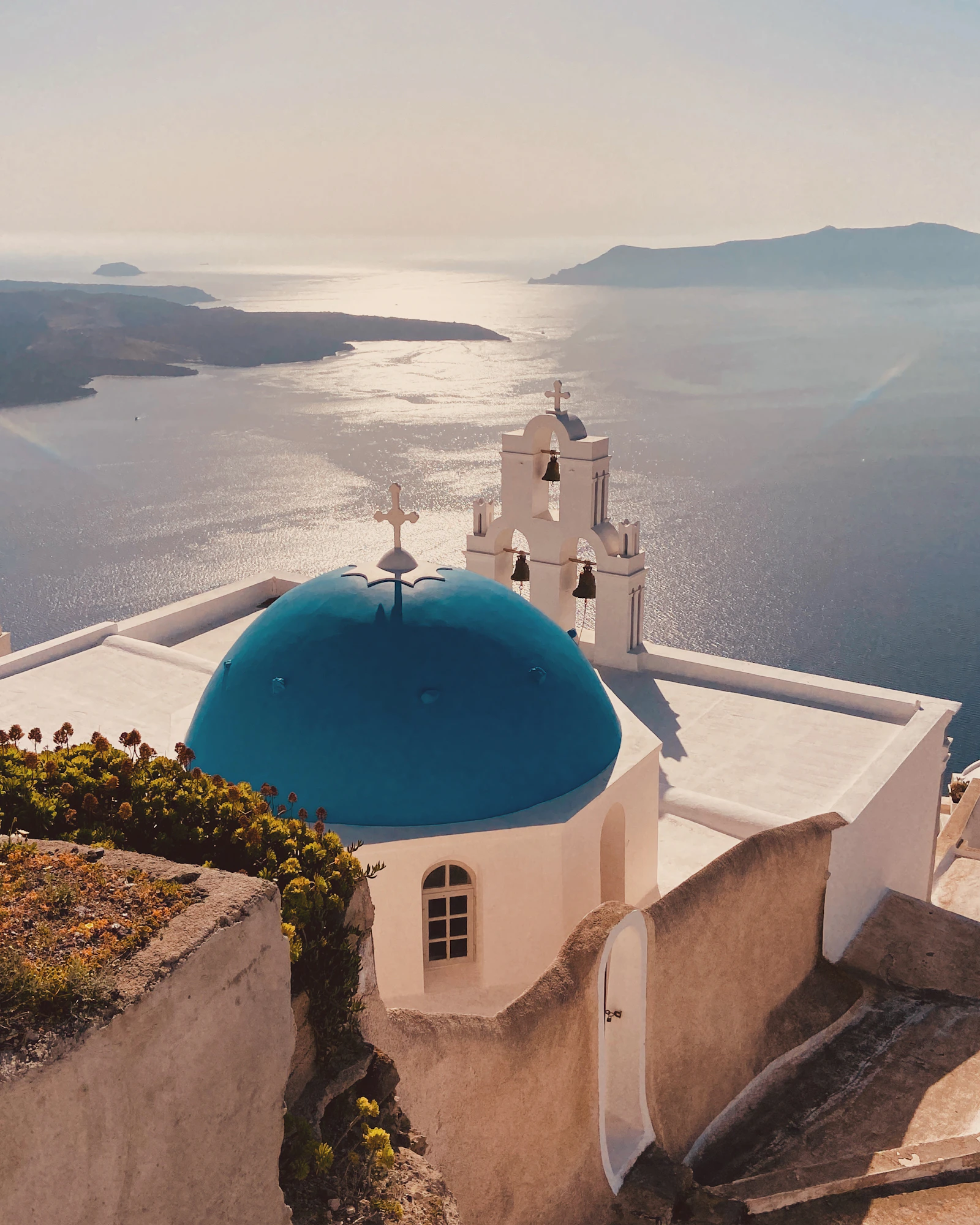 Blue-domed church in Santorini, Greece, bathed in golden hour light