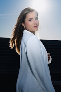 A woman poses, lit by bright sunlight.