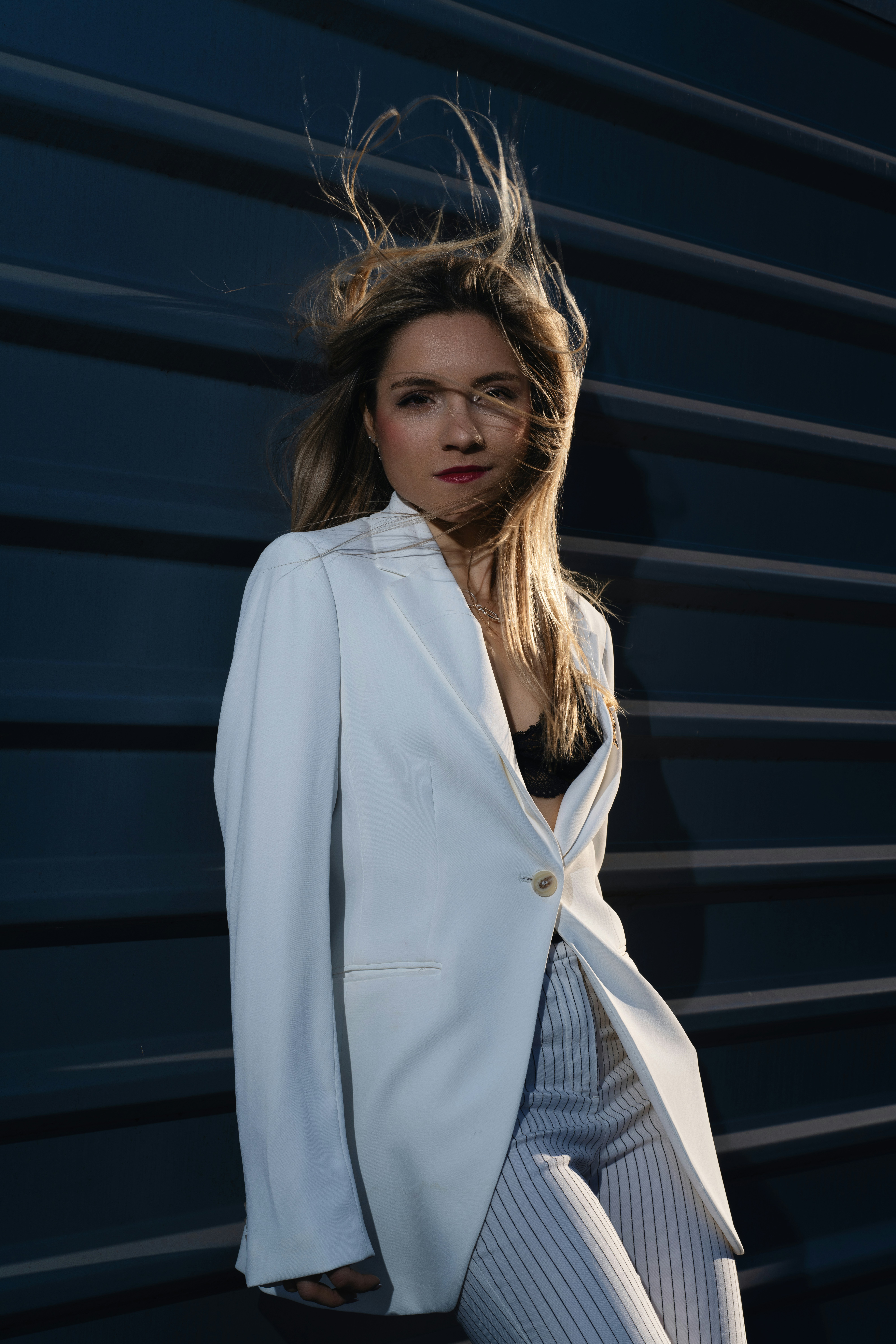 Blonde woman poses in white blazer.
