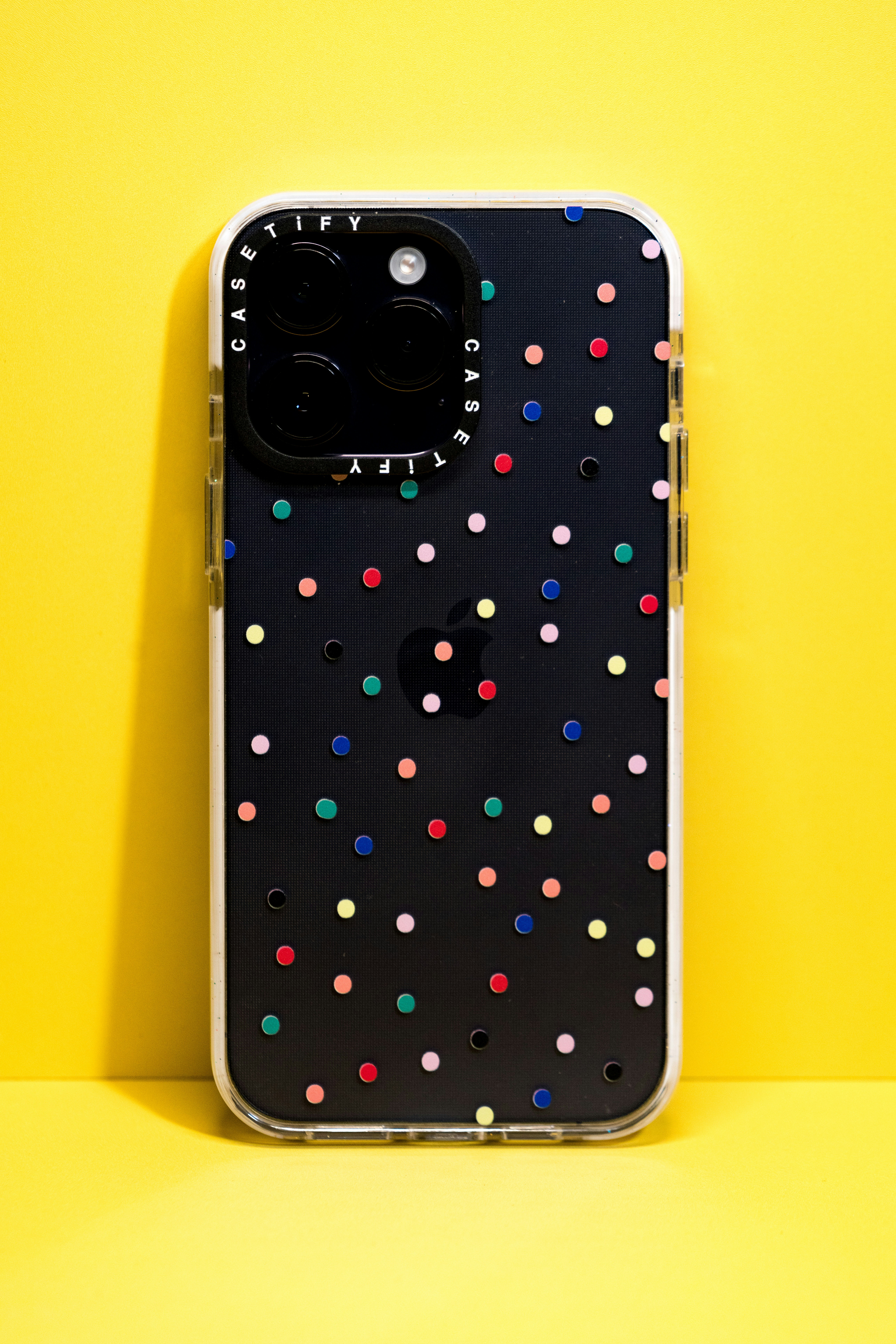 A black iPhone with a colorful polka-dot case.