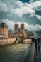 Notre dame cathedral stands tall under a cloudy sky.