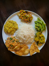 A plate of rice and various south asian dishes.