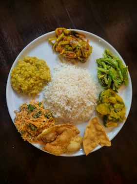 A plate of rice and various south asian dishes.