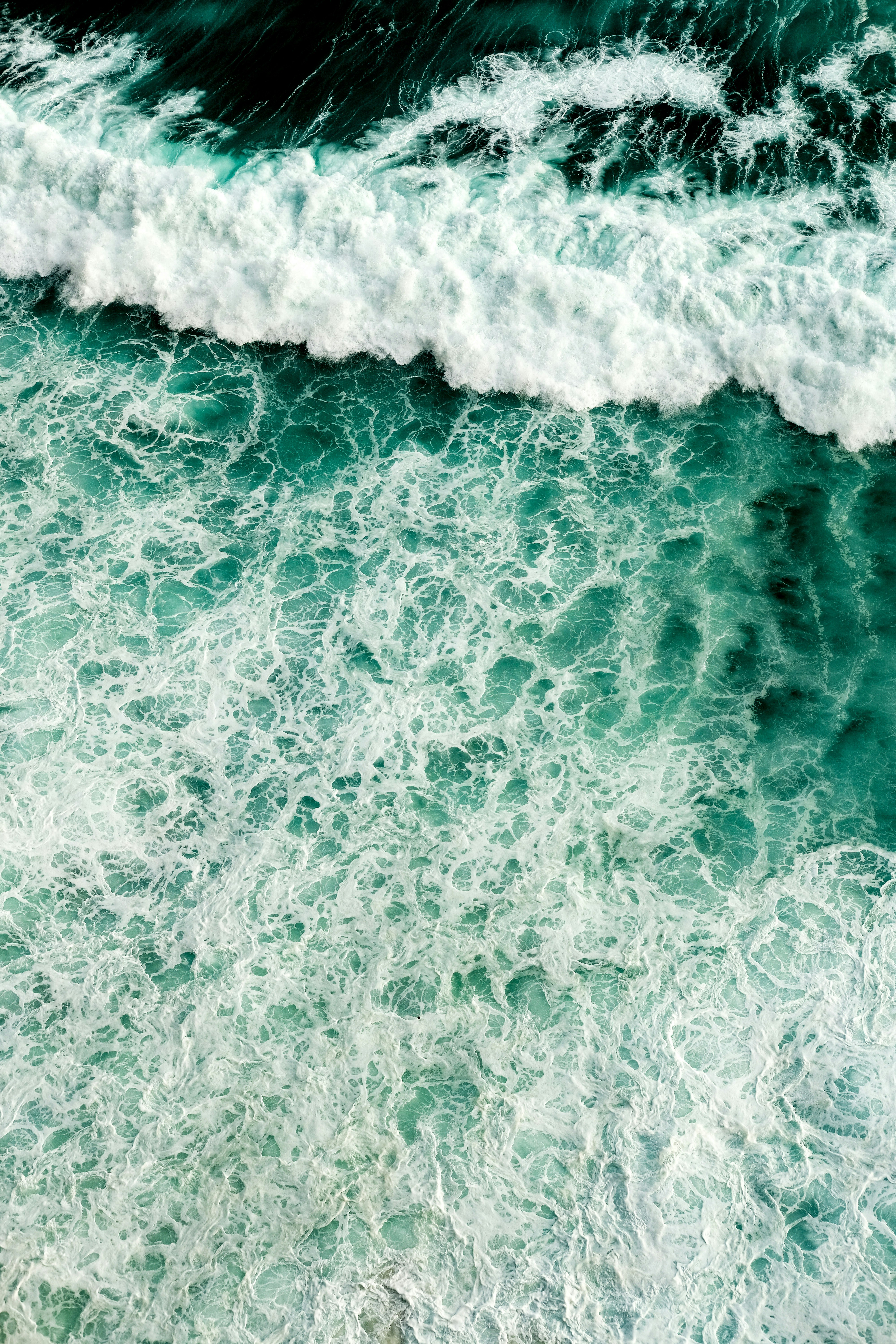 Onde bianche si infrangono su una superficie oceanica turchese.