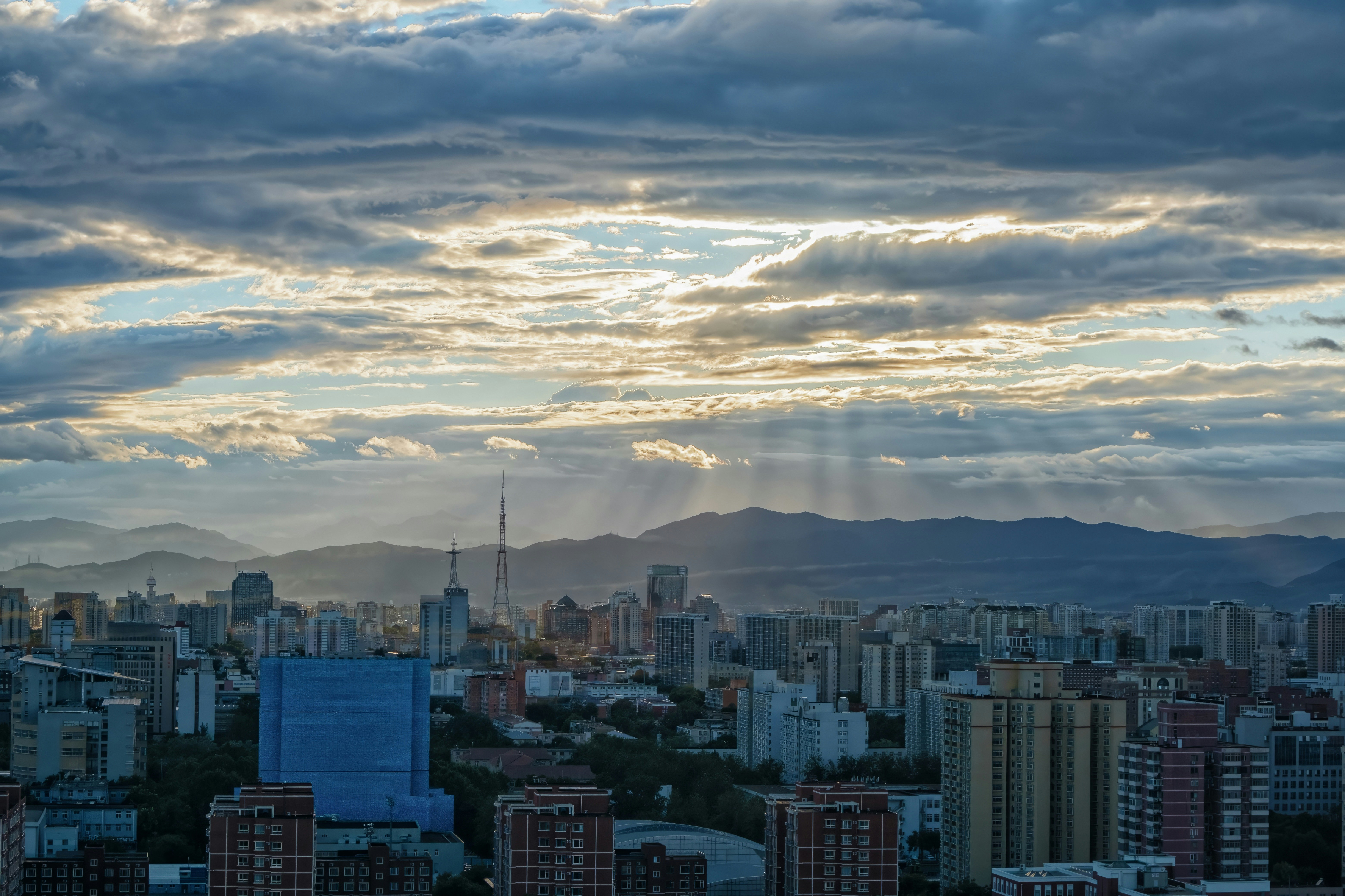 Sunbeams pierce through the clouds over a cityscape.