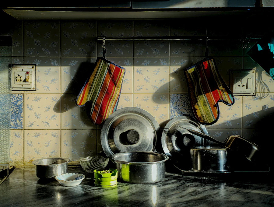 Two heat-safe oven mitts hanging above kitchen pots and pans