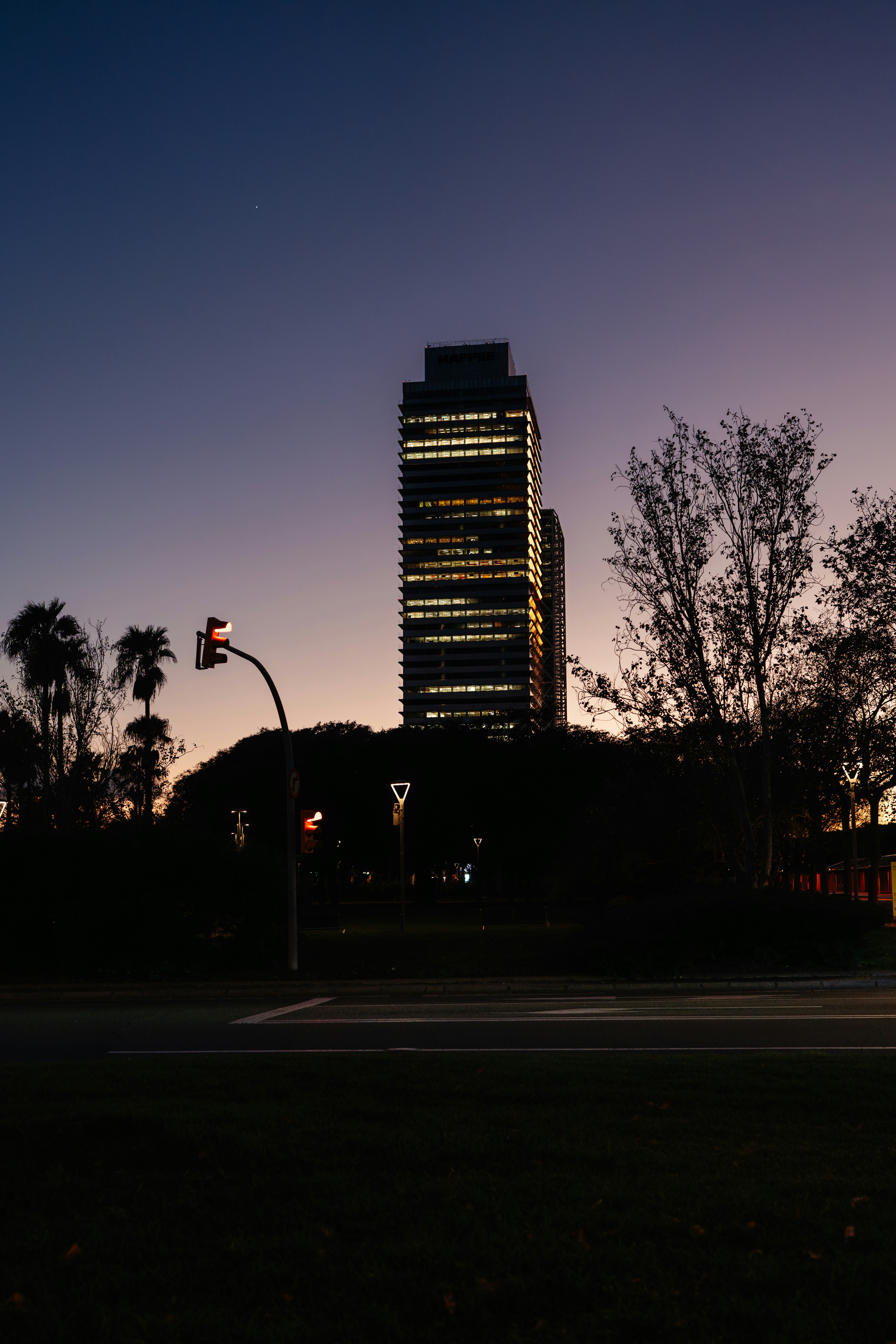 A tall building lights up against a twilight sky.