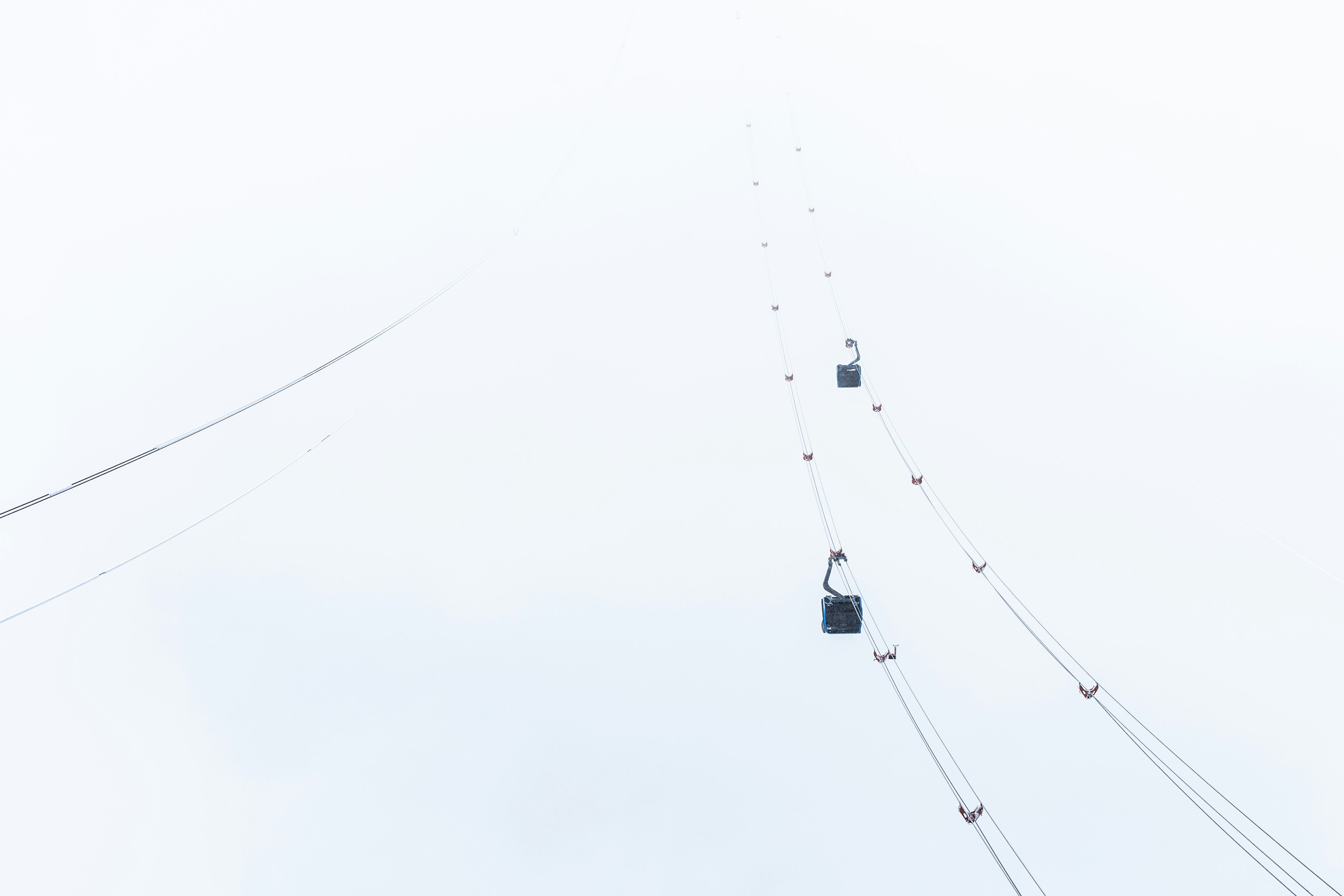 Cable cars traverse a misty, white landscape.
