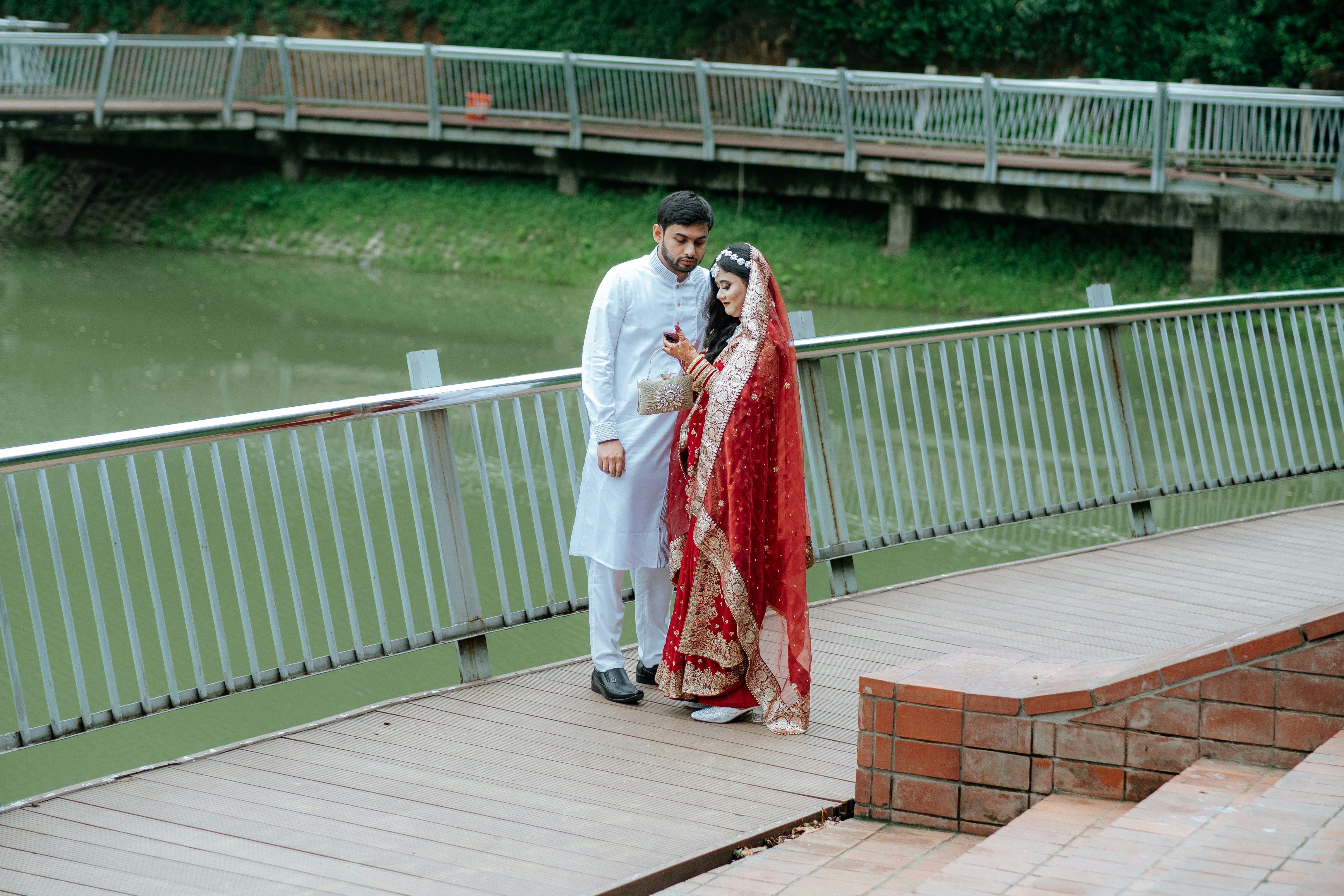 A newly married couple poses on a bridge.