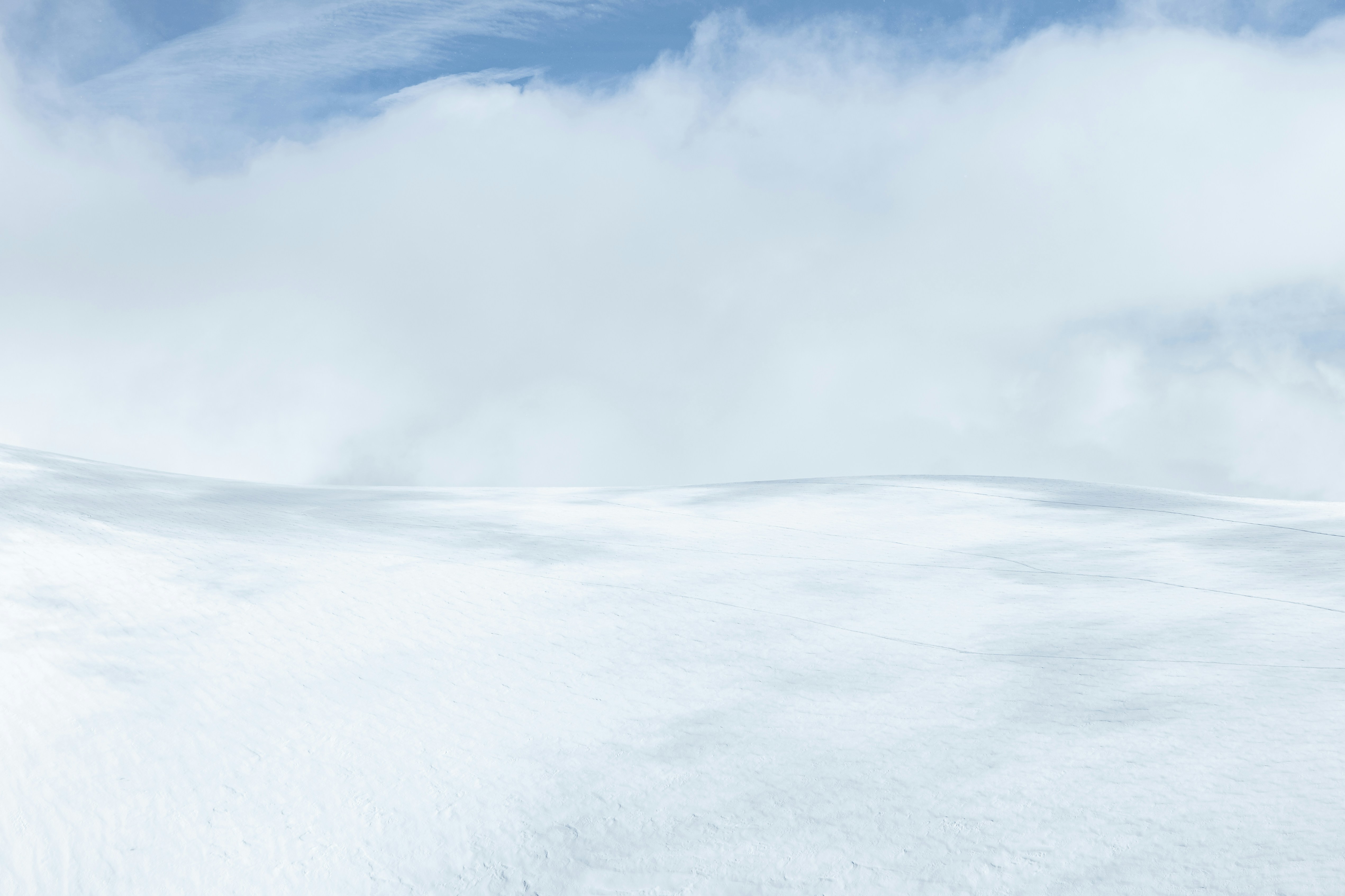 Clouds and sky dominate a snow-covered landscape.